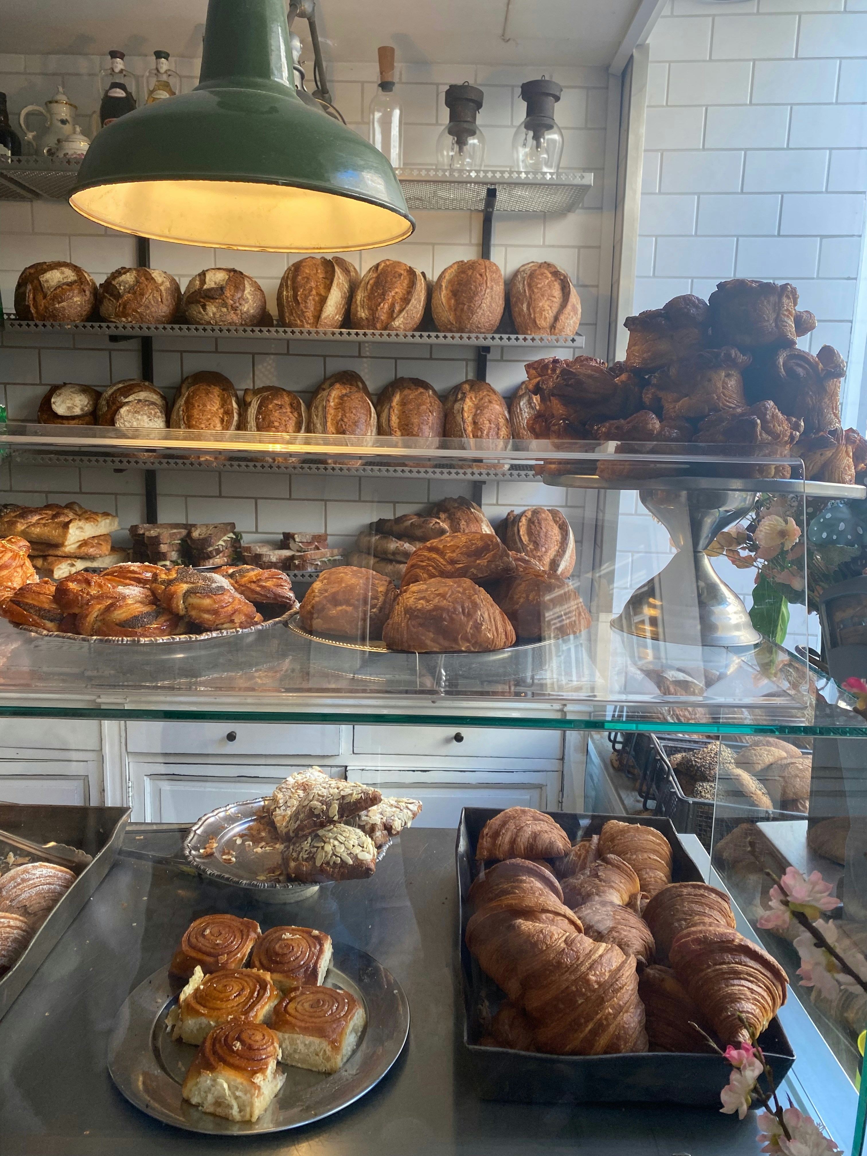 Assorted fresh bakery items and chocolates on bright white bakery counter, natural daylight