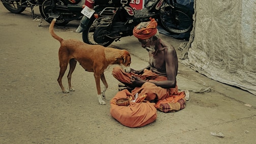 A man sitting on the ground next to a dog