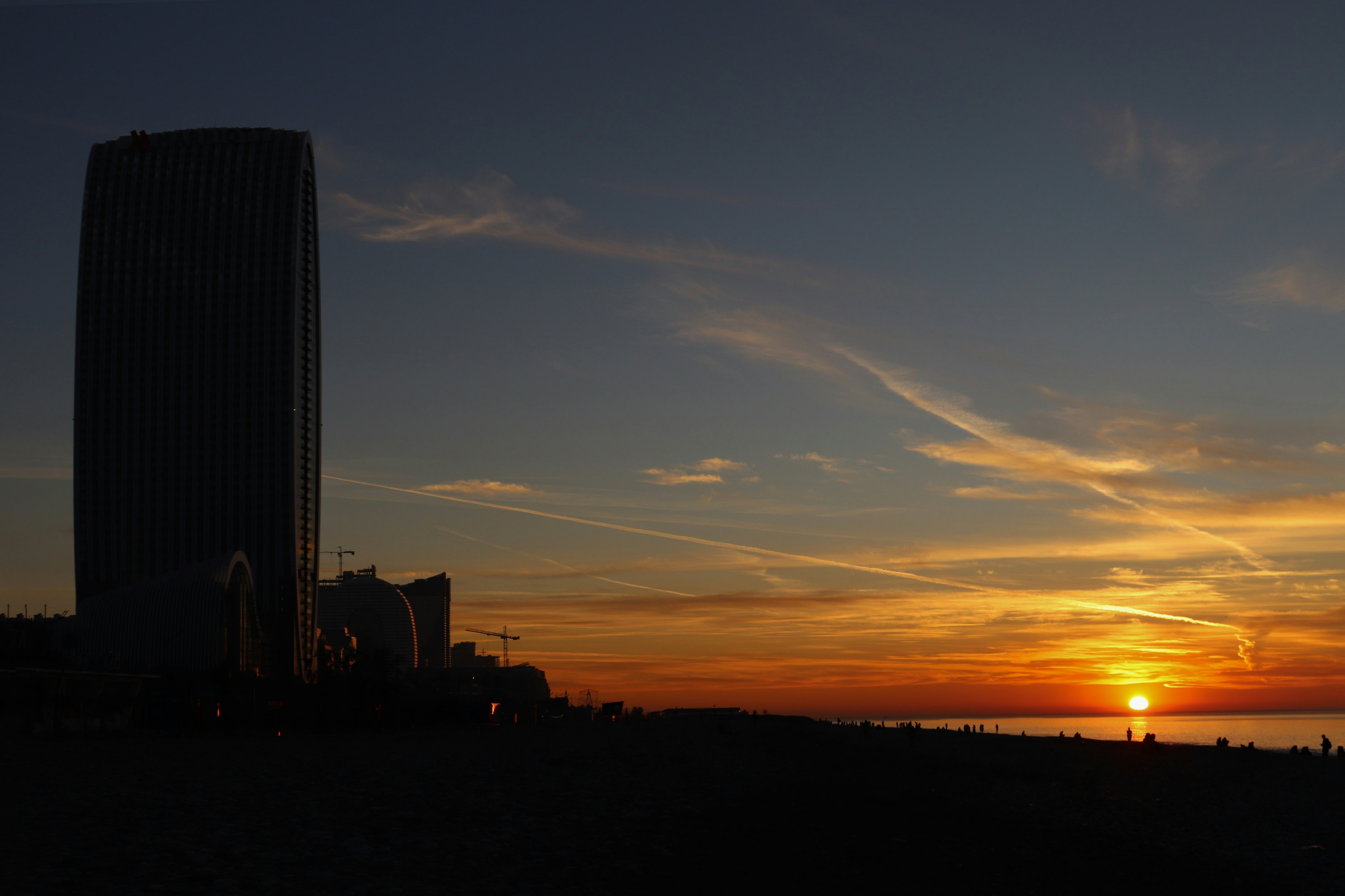 The sun is setting behind a tall building photo Free Image on