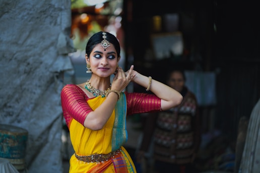 A woman in a yellow and red sari talking on a cell phone