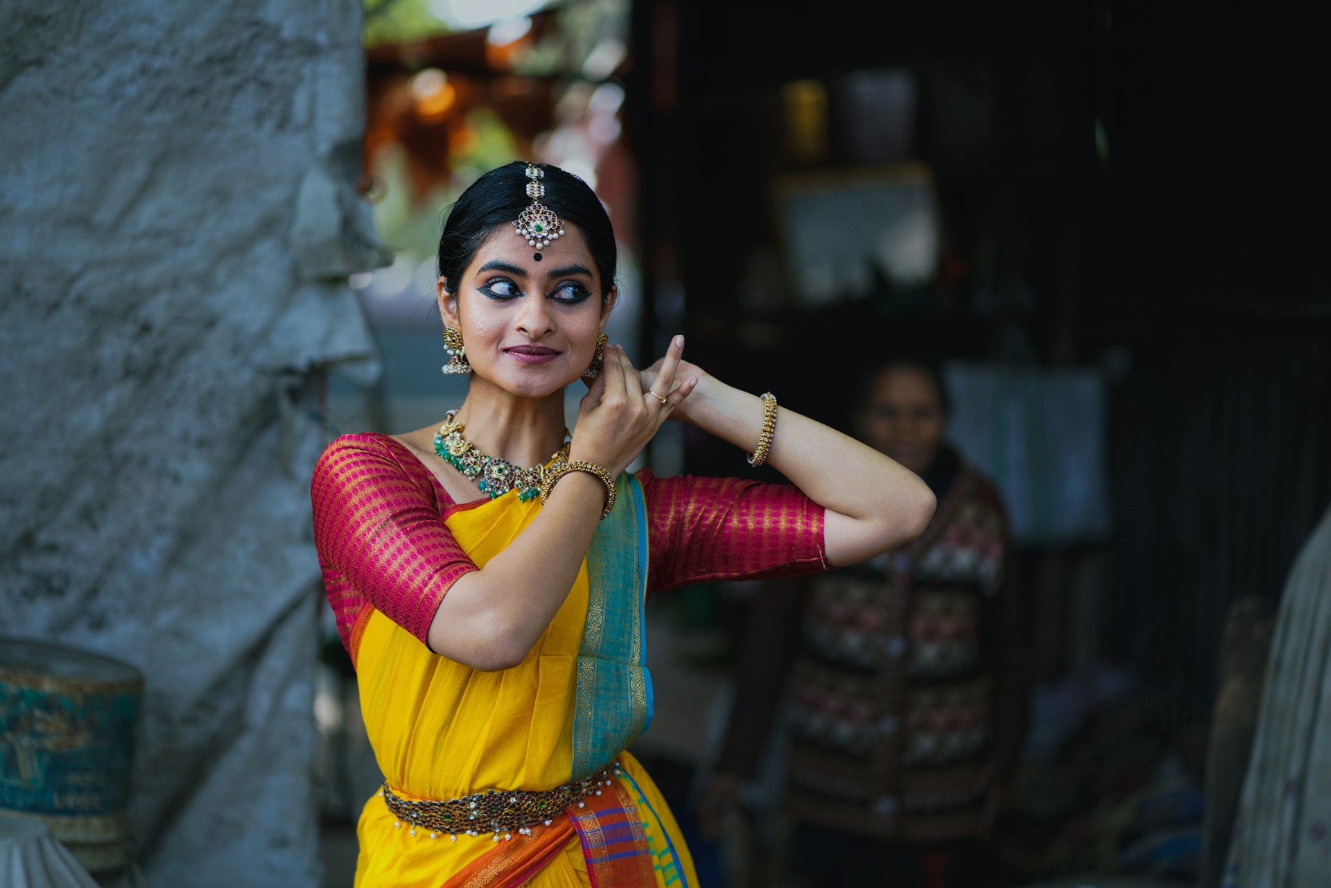 A woman in a yellow and red sari talking on a cell phone