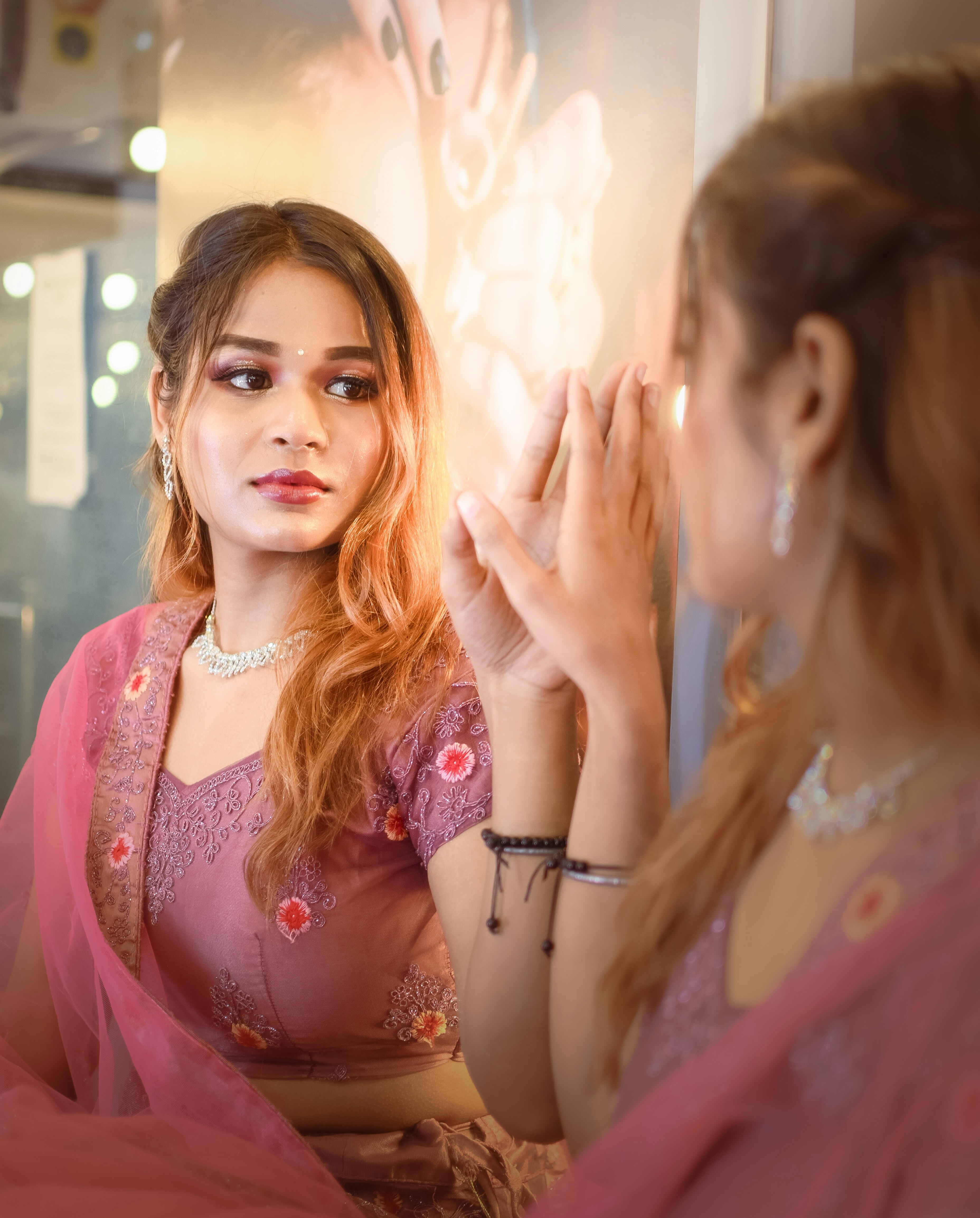 A woman in a pink sari looking at herself in the mirror