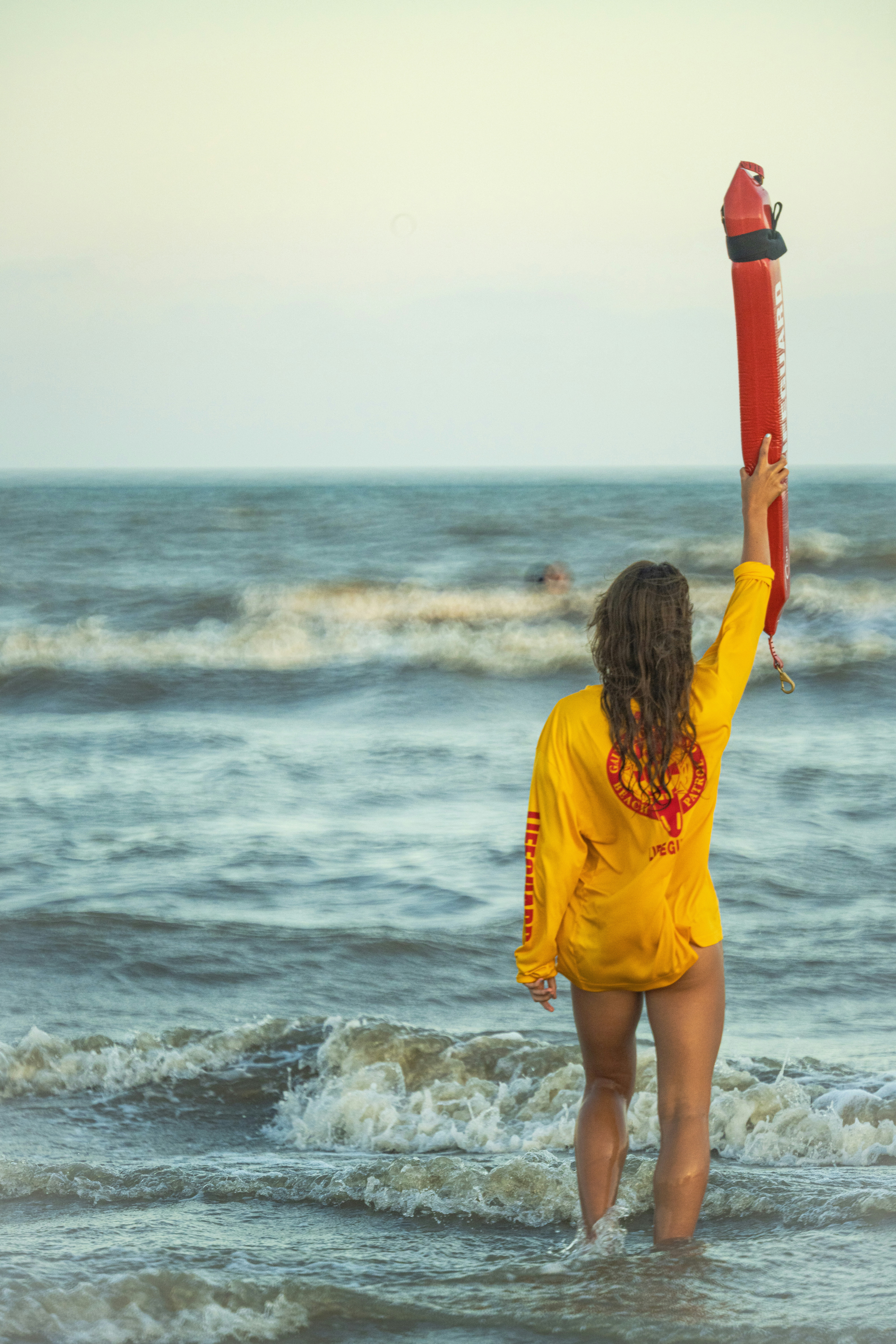 A woman standing in the ocean holding a life preserver