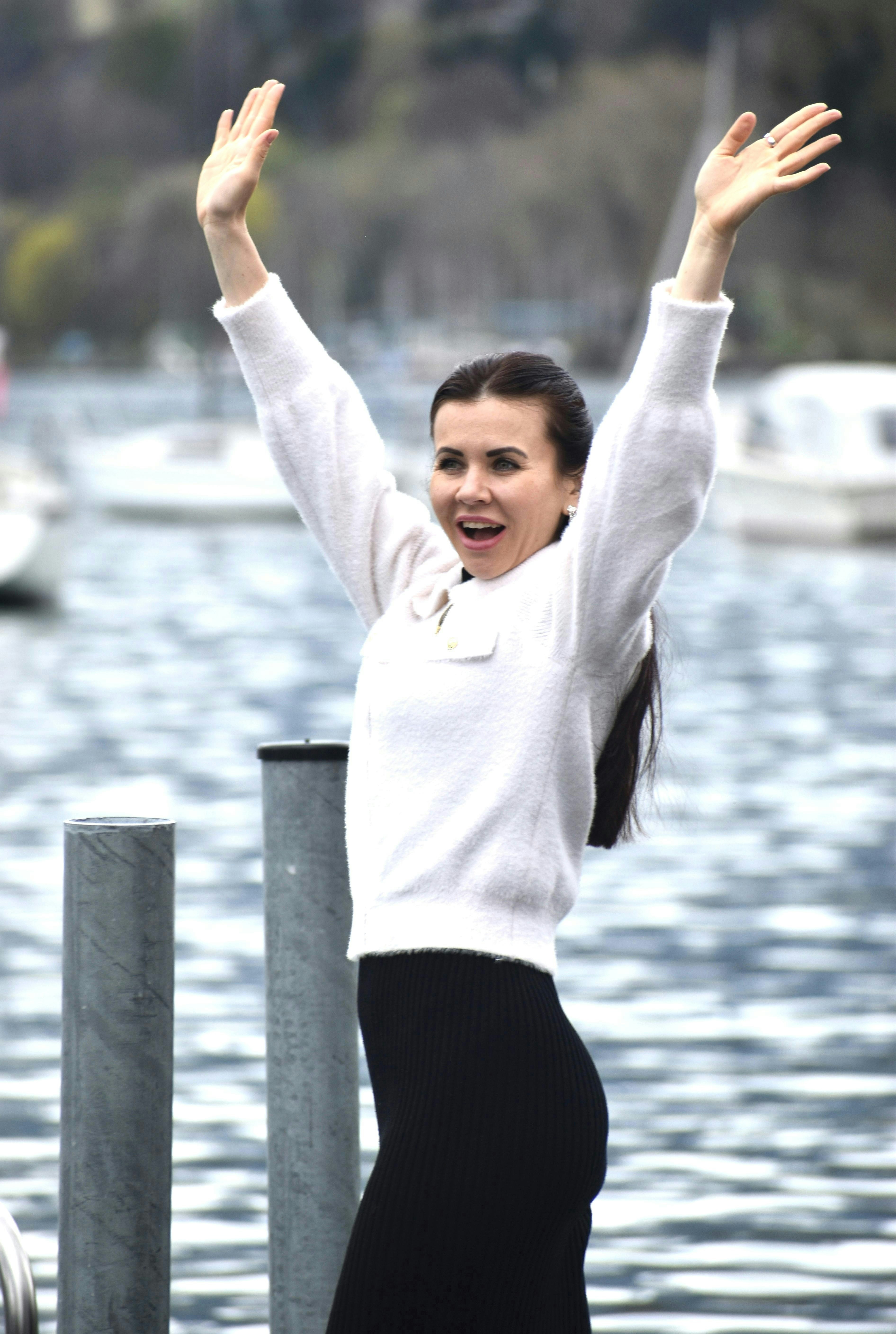 A woman standing on a dock with her arms in the air