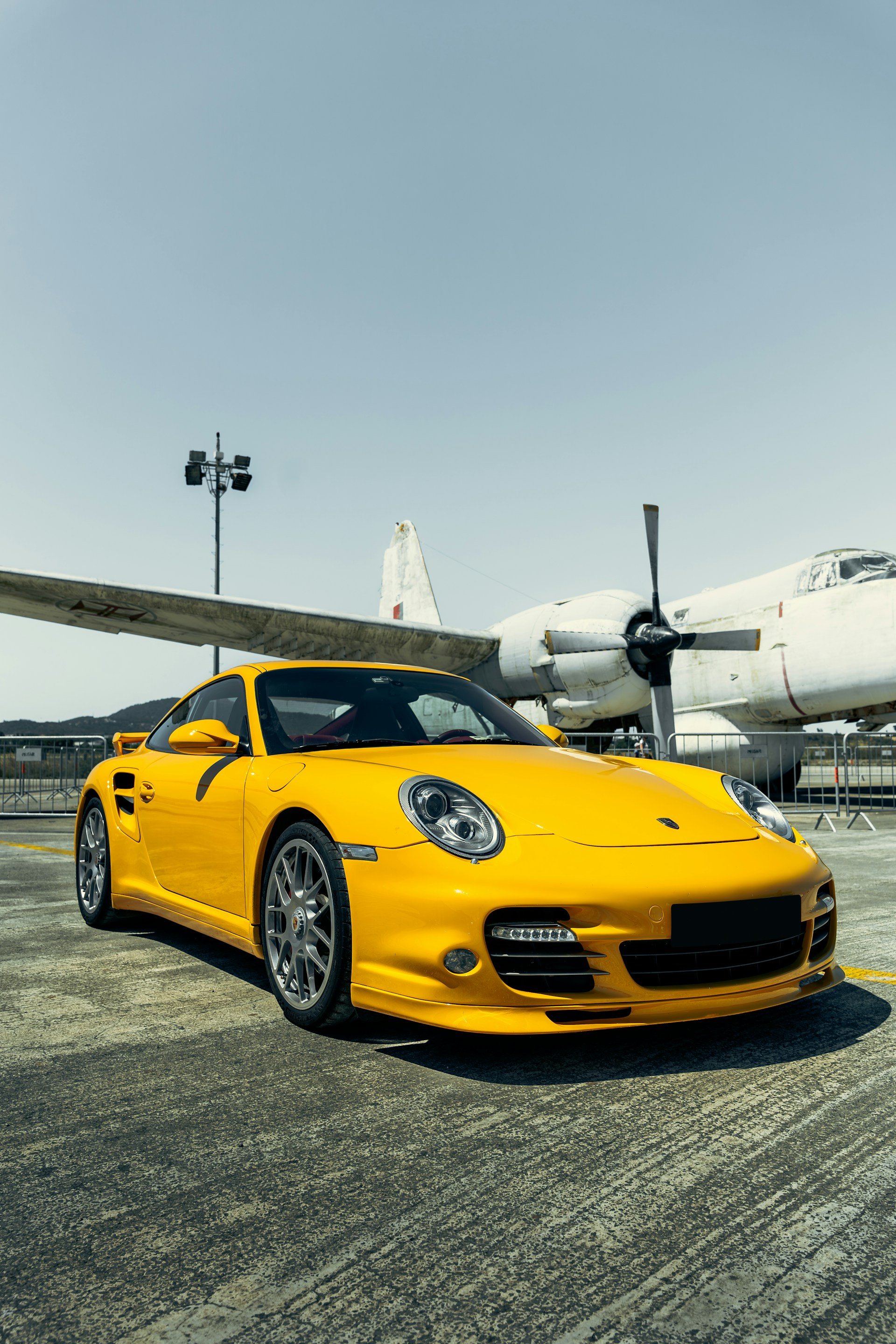 A yellow sports car parked in front of an airplane