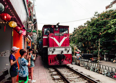 A red train traveling down train tracks next to a crowd of people
