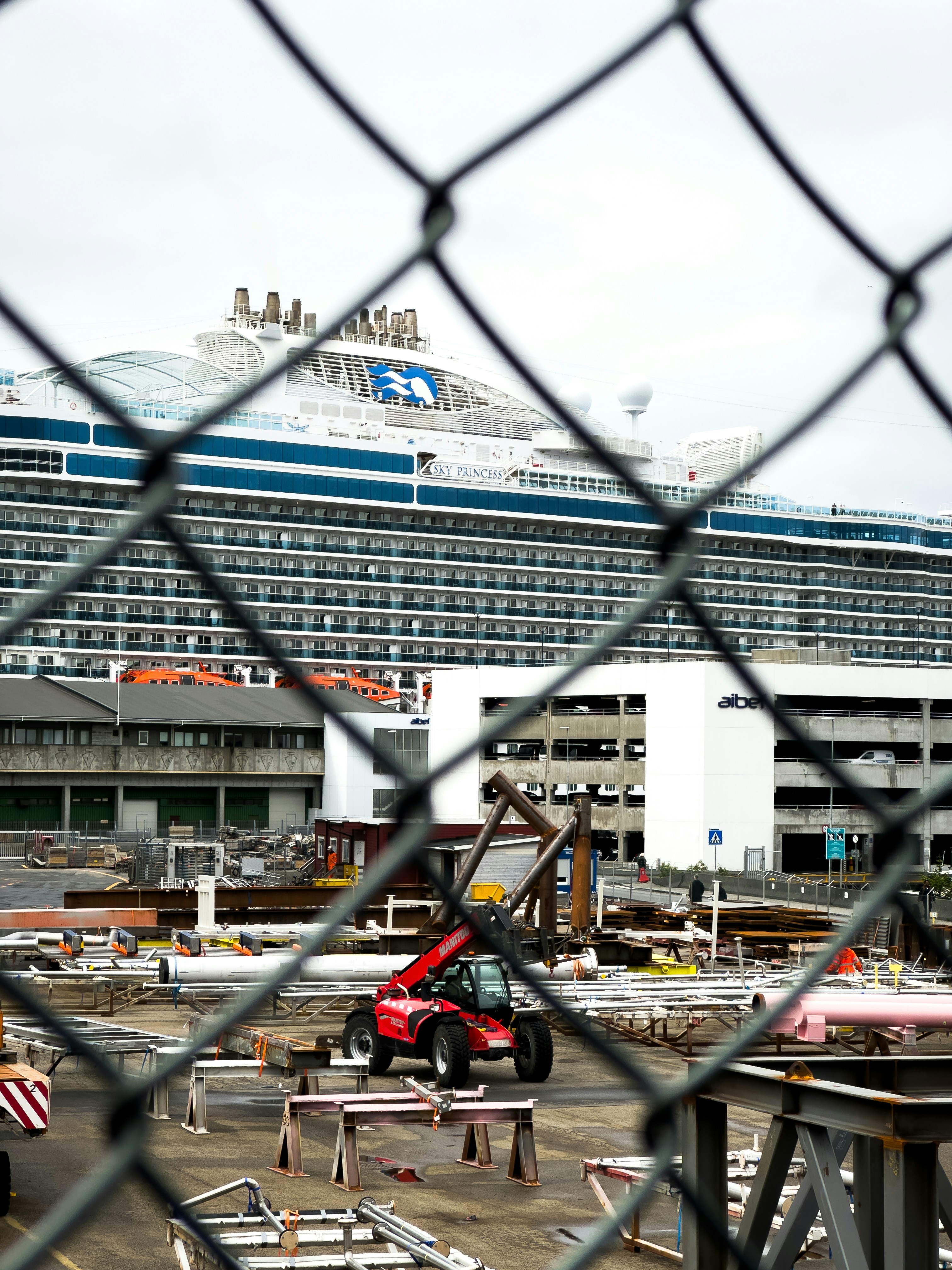 A large cruise ship in the background behind a chain link fence