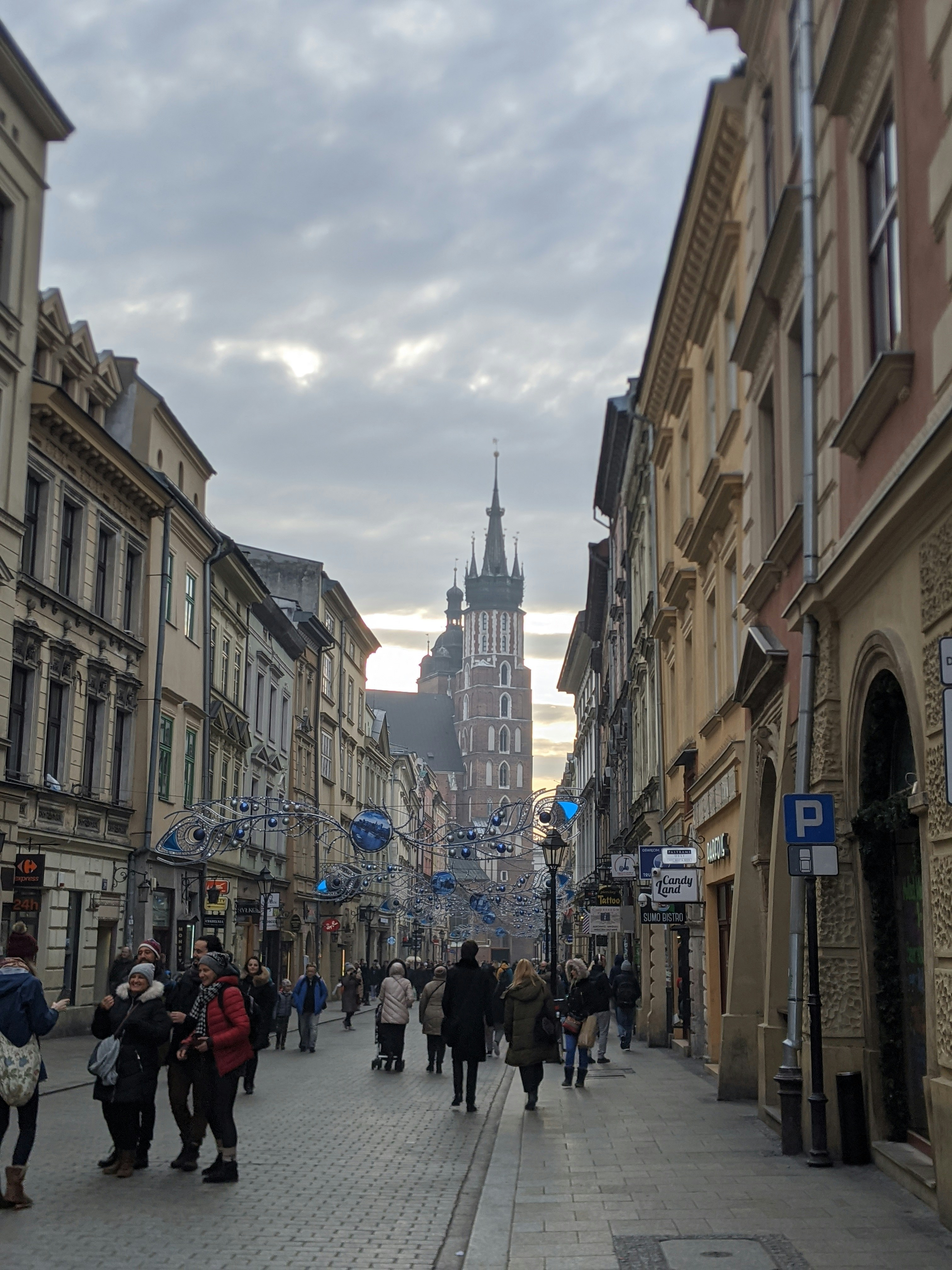 A group of people walking down a street next to tall buildings