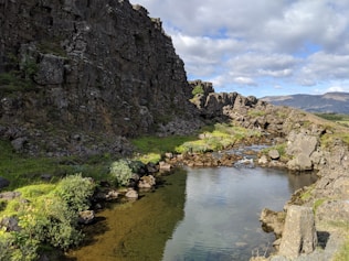 A body of water surrounded by rocks and grass