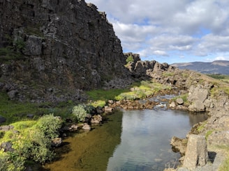 A body of water surrounded by rocks and grass