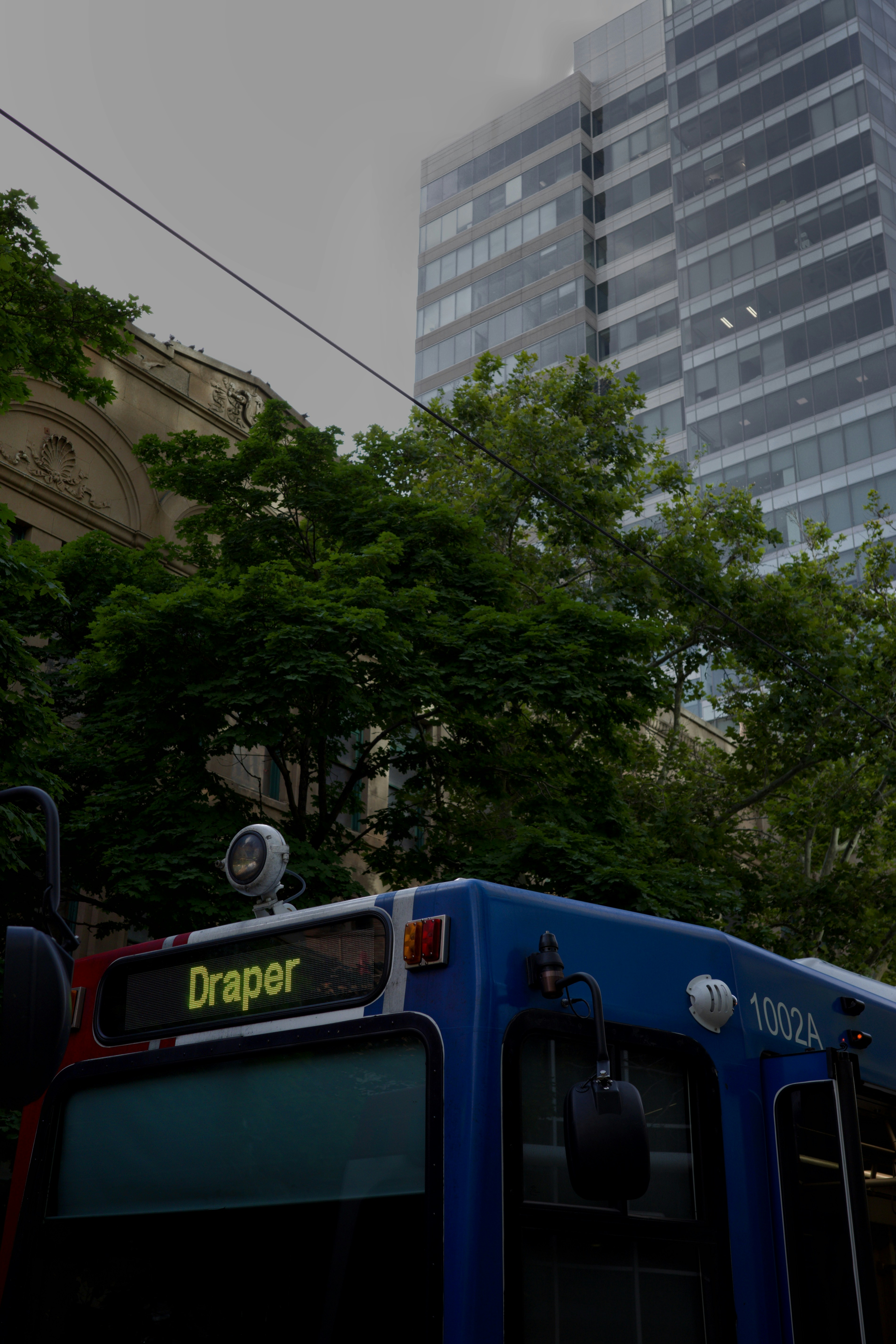 A blue bus driving down a street next to tall buildings