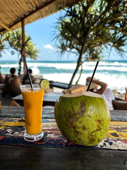 A glass of orange juice next to a coconut on a table
