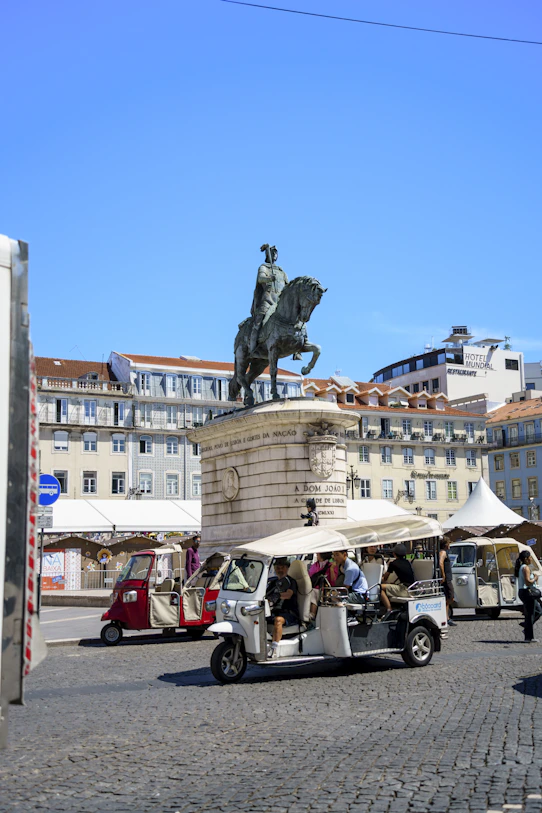 A golf cart parked in front of a statue of a man on a horse