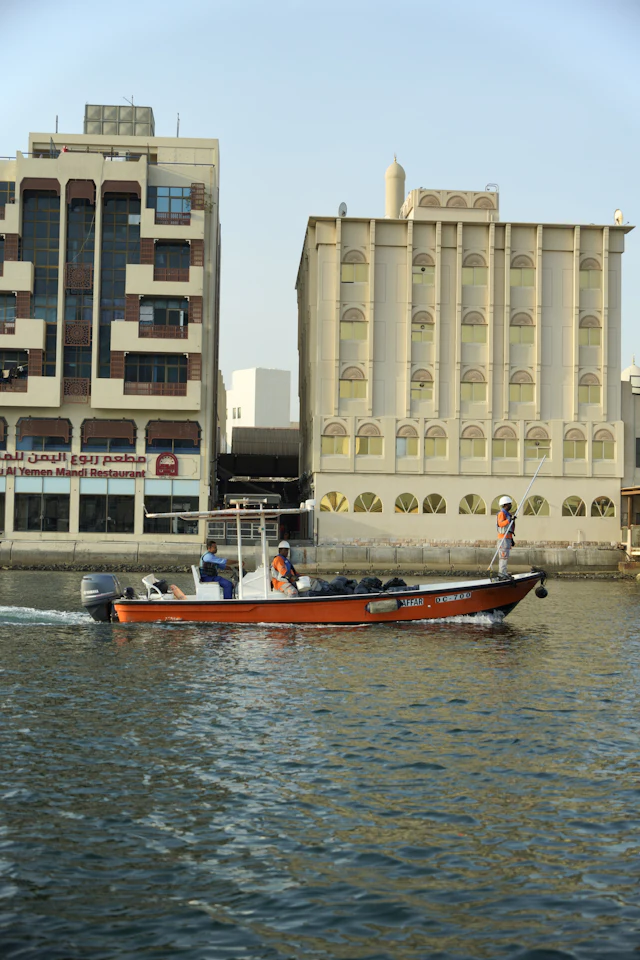A traditional abra crossing Dubai Creek past the old wind-tower buildings of Bur Dubai.