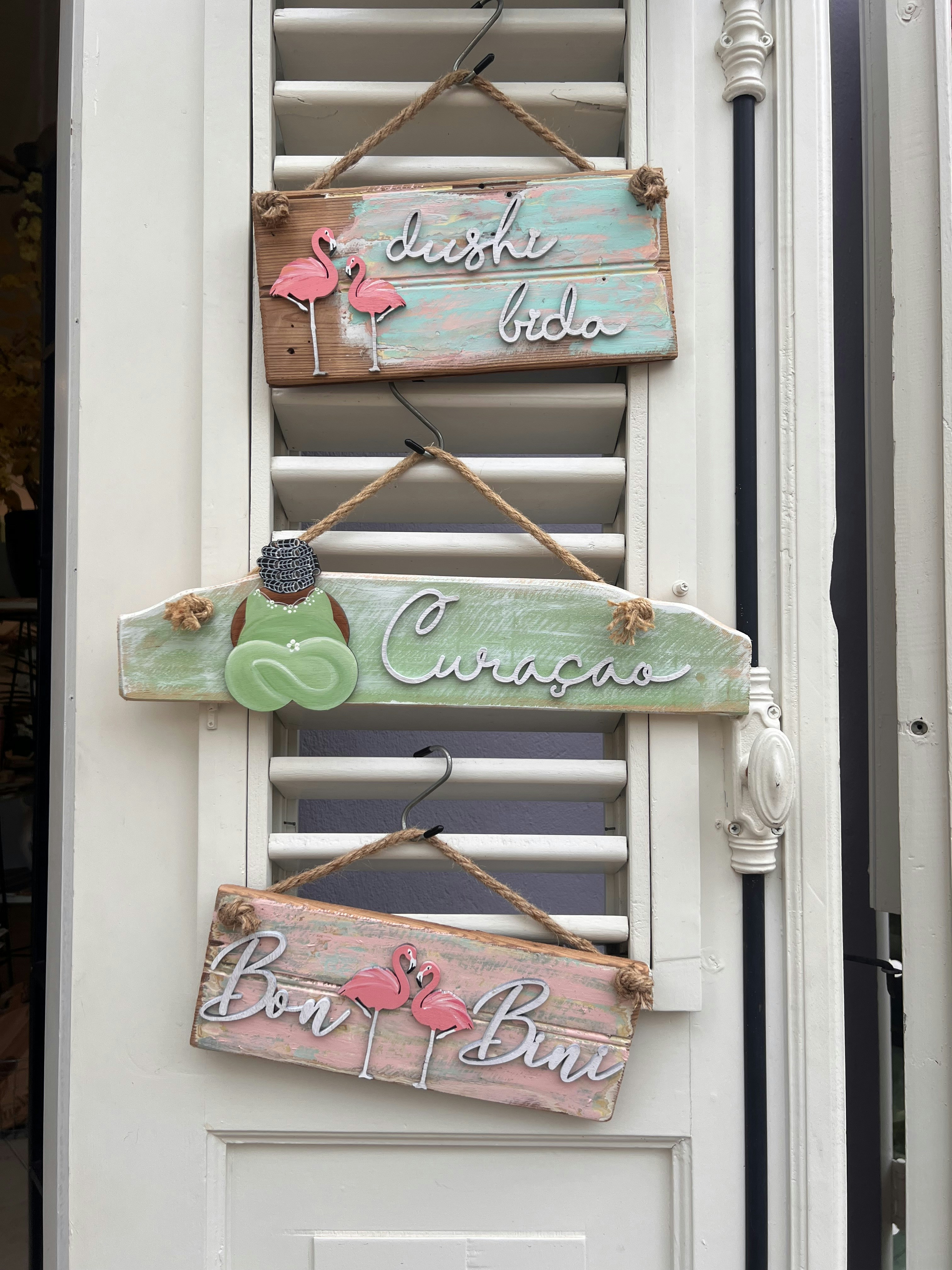 A white door with three wooden signs hanging from it's side
