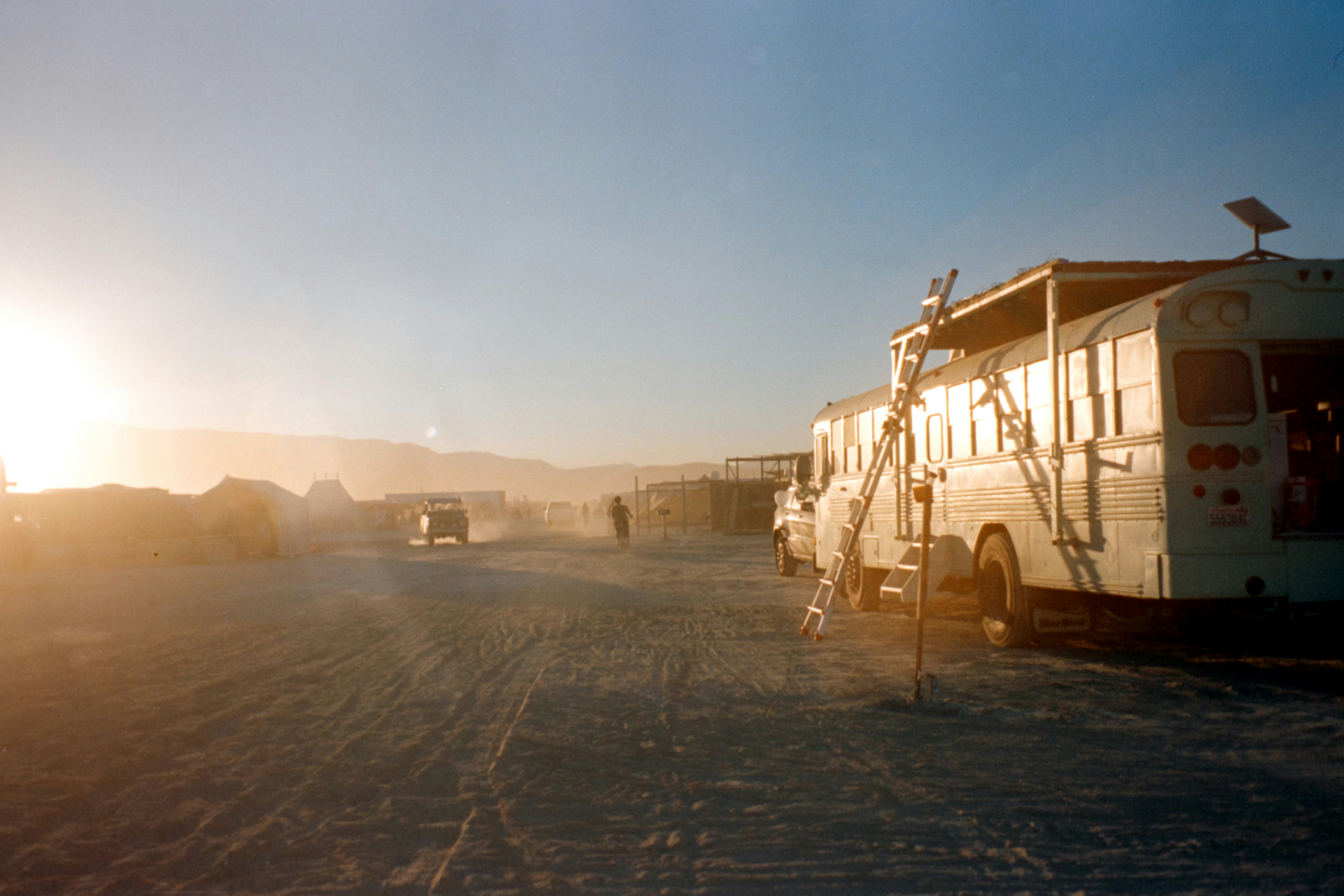A group of buses driving down a dirt road