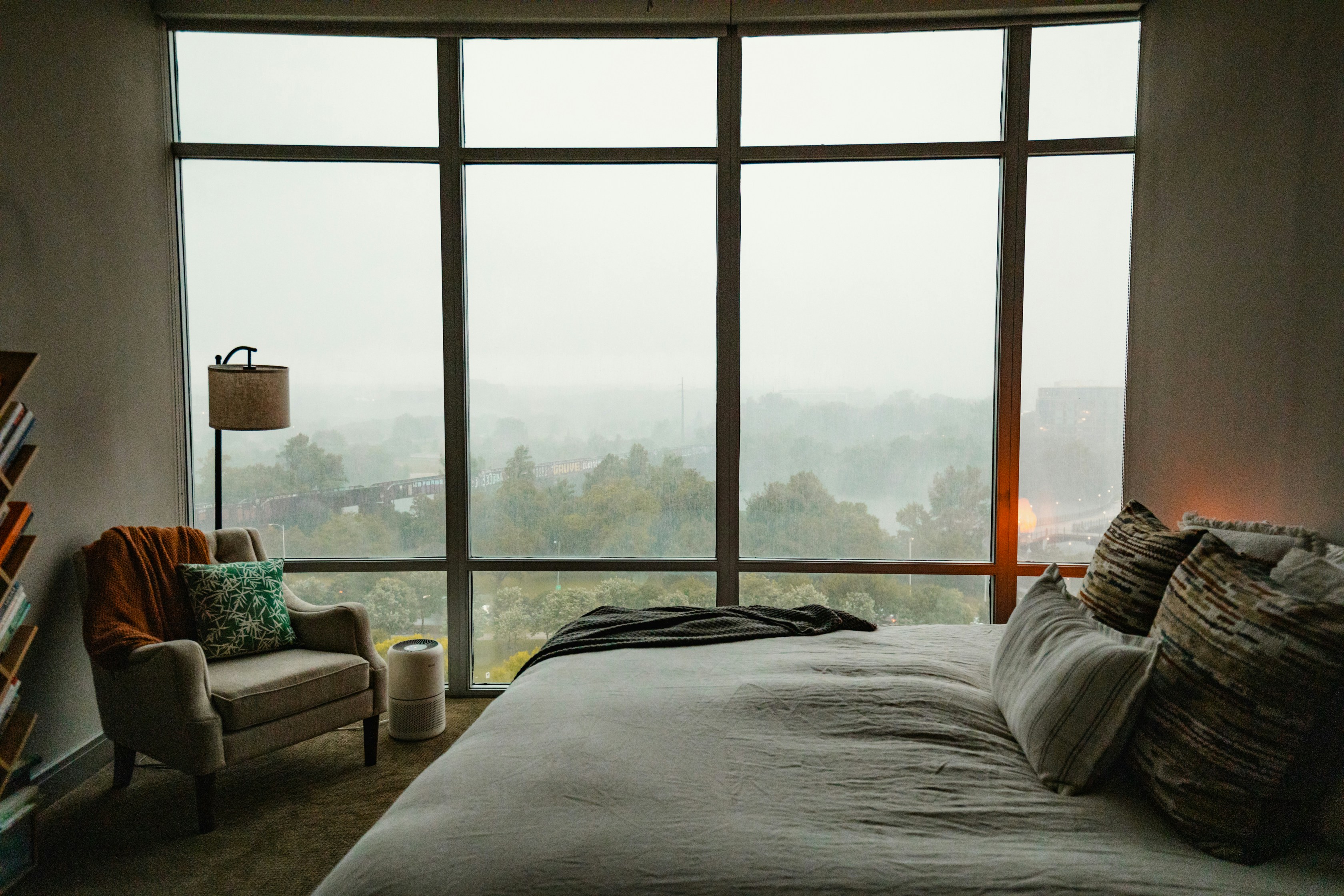 A bedroom with a large window overlooking a city