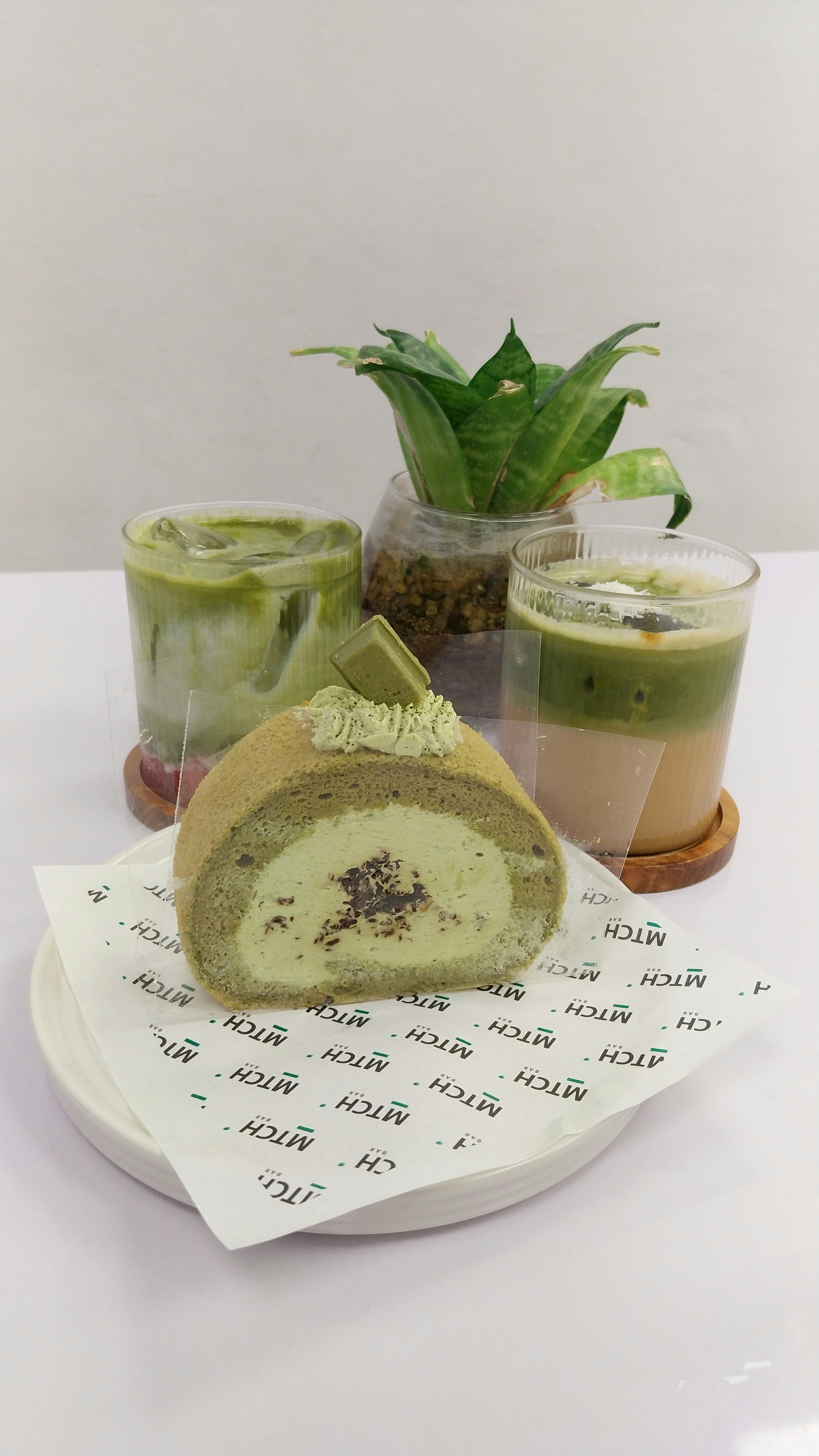 A white plate topped with a cake next to a cup of coffee