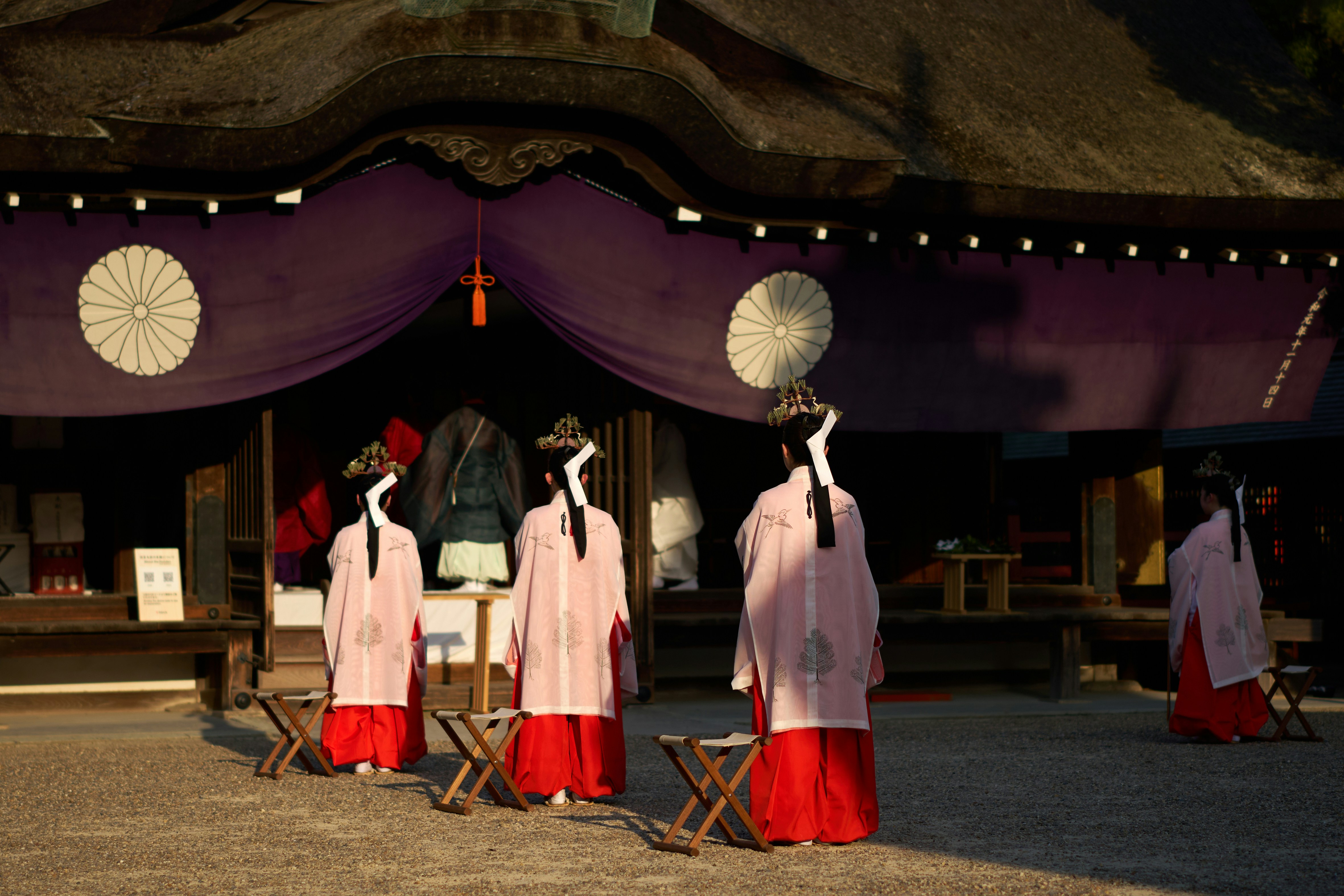 A group of women in pink and red dresses standing in front of a building