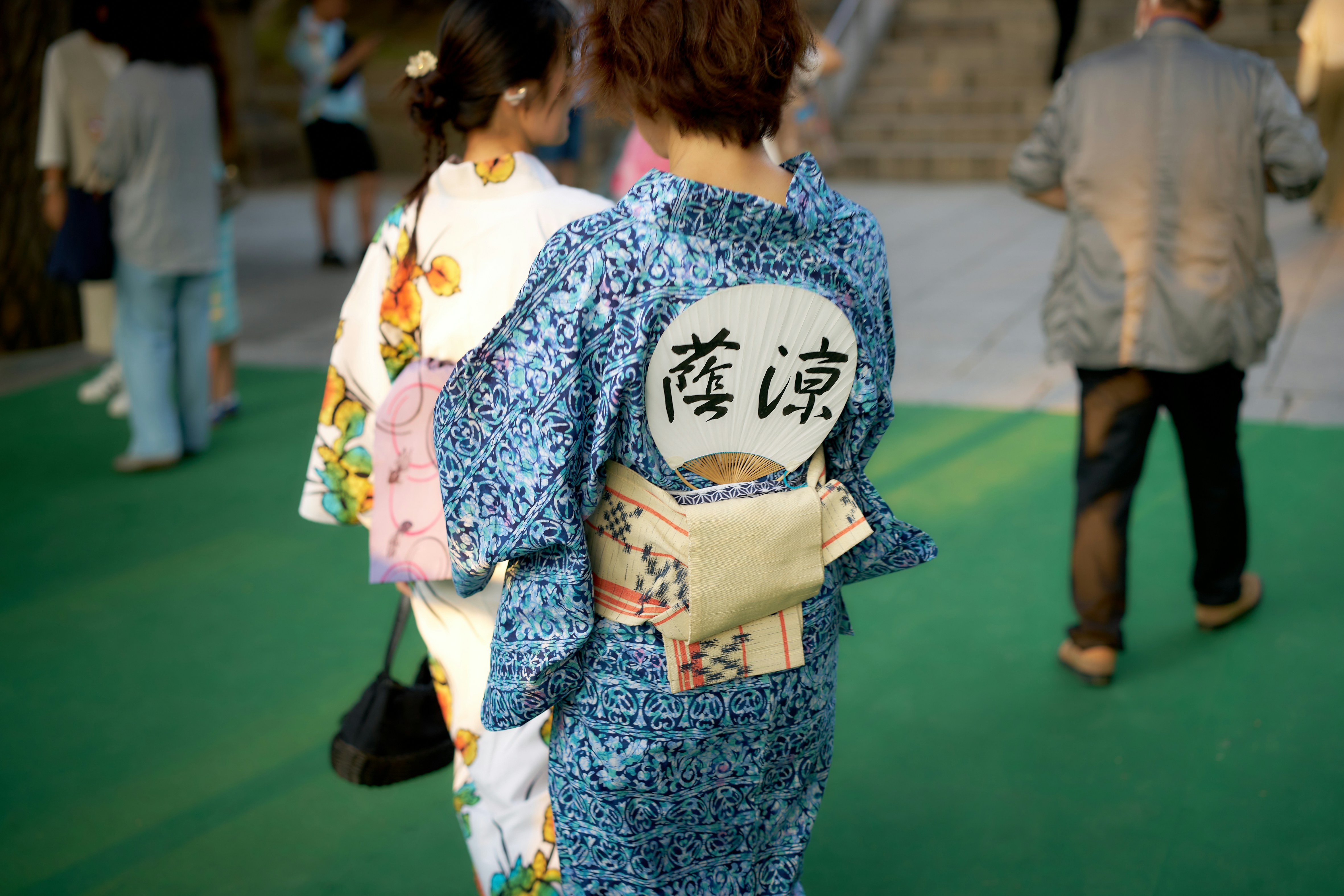 A woman in a kimono walking down a green carpet