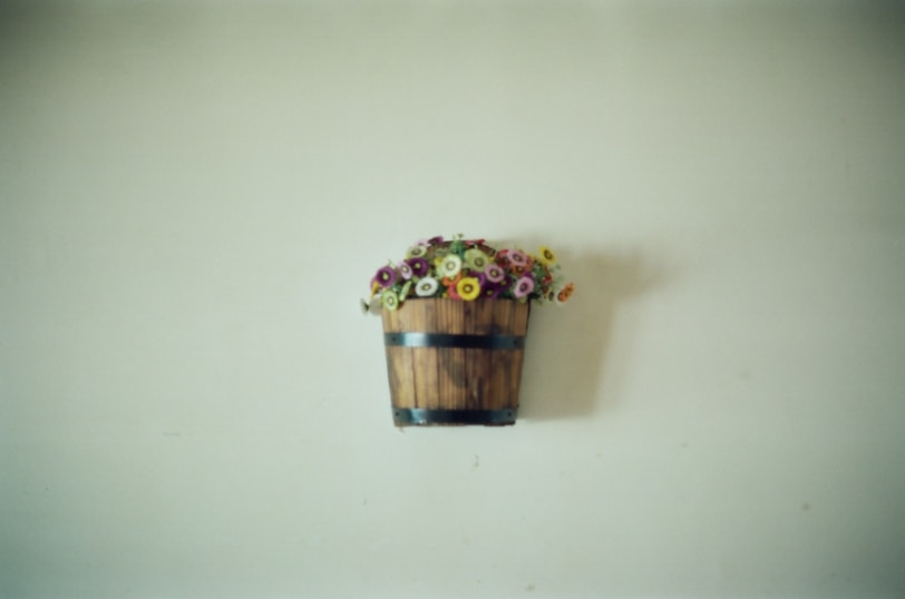 A wooden bucket with flowers hanging on a wall