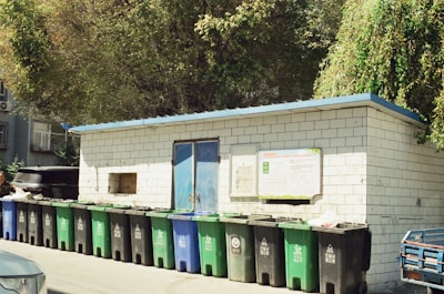 A row of green and blue trash cans next to a building