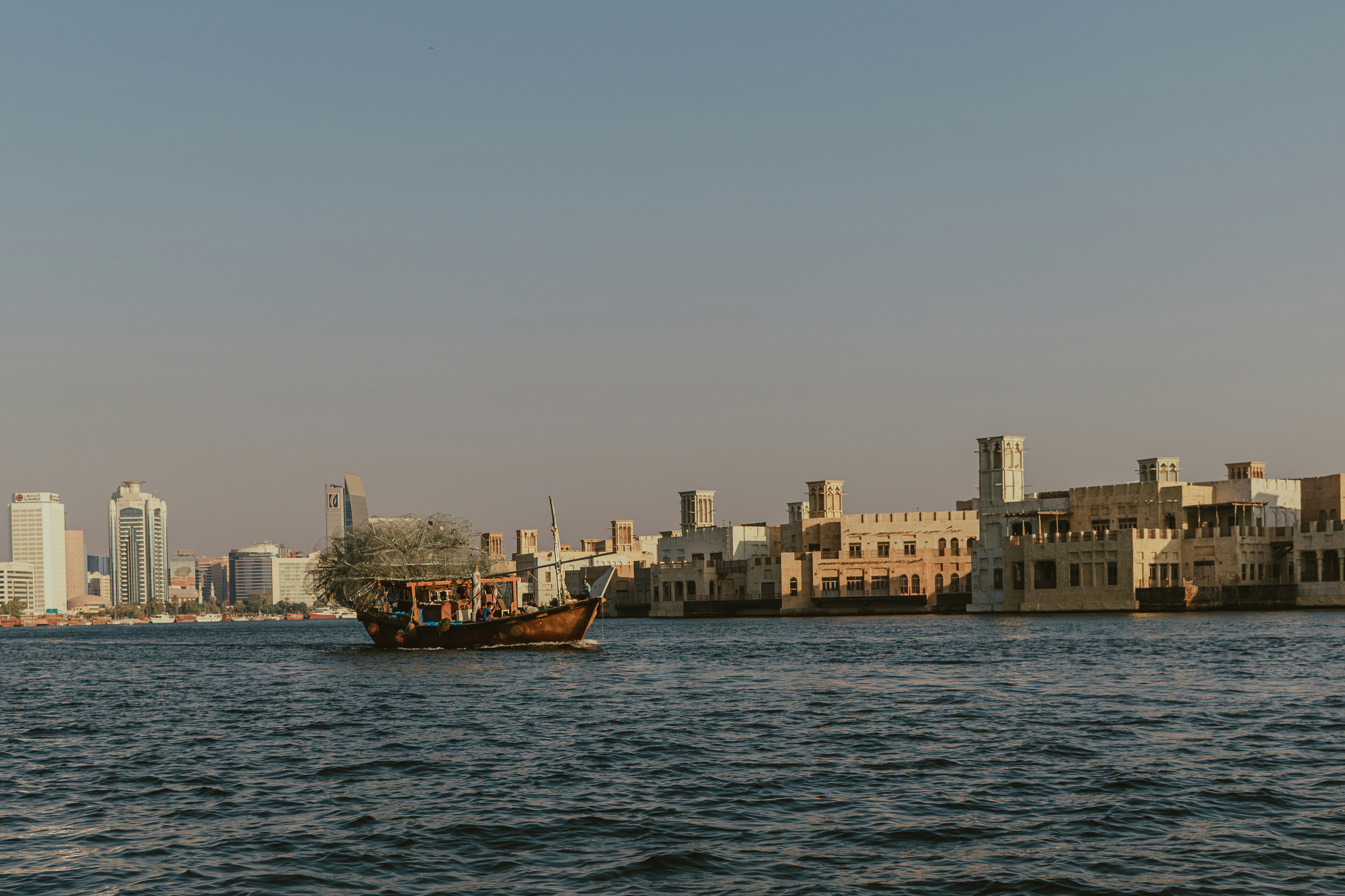 A large body of water with a city in the background, Waterfront harbor skyline with traditional drifting fishing boat on the sea