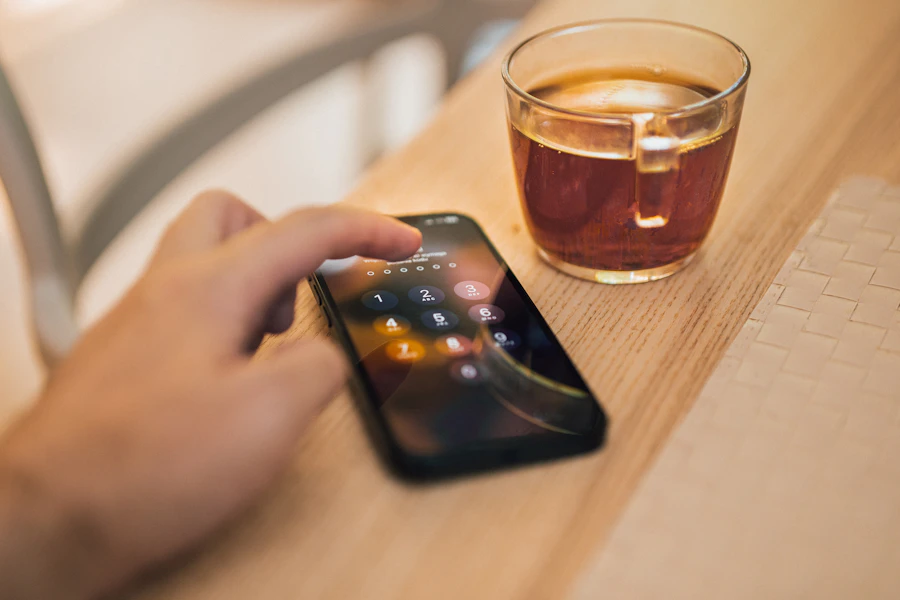 Een hand houdt een smartphone vast naast een kop koffie