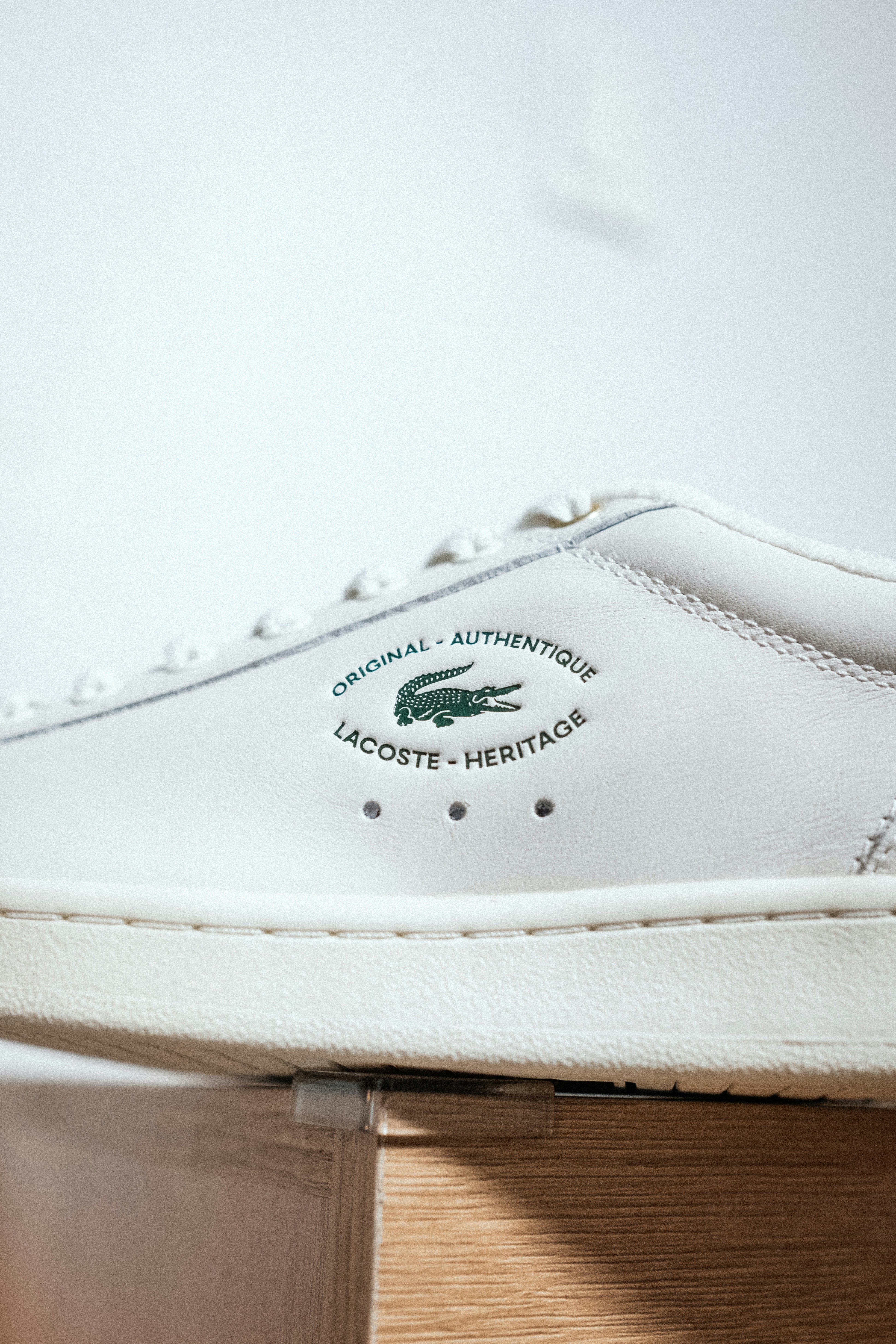 Une chaussure de tennis blanche posée sur une table en bois