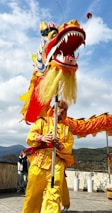 A man in a yellow dragon costume holding a stick