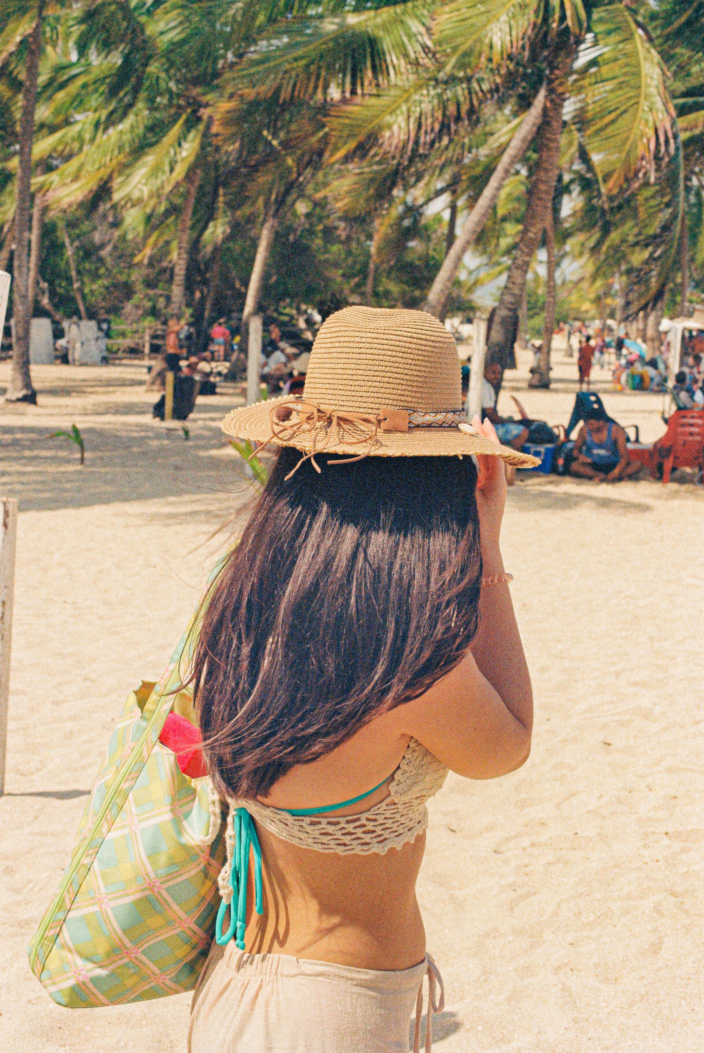A woman in a hat is sitting on the beach