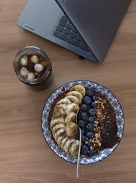 A blue and white plate topped with bananas and blueberries