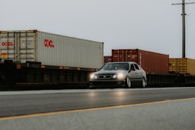 A car driving down a road next to a train