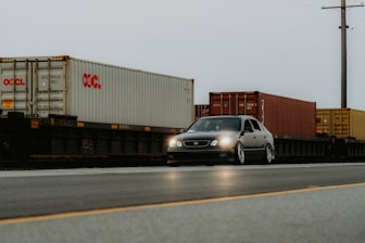 A car driving down a road next to a train