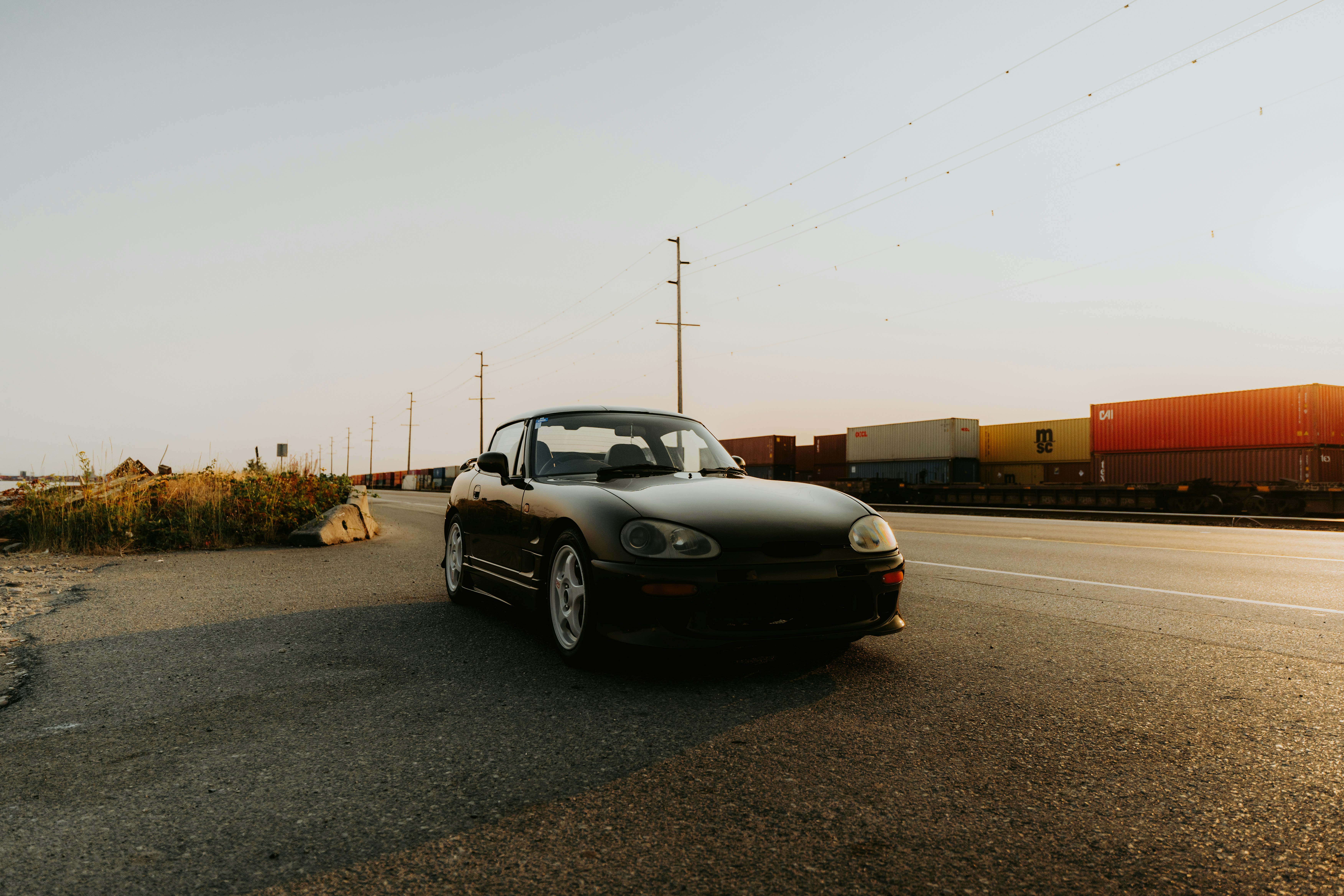 A car driving down a road next to a train
