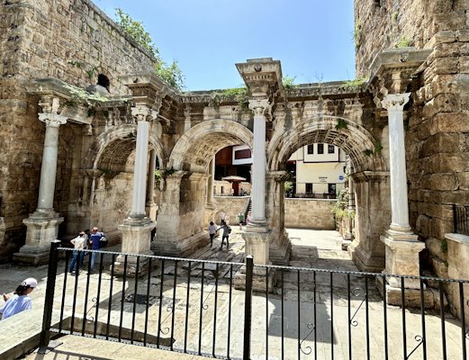 A group of people standing around a stone building — Side, Turkey