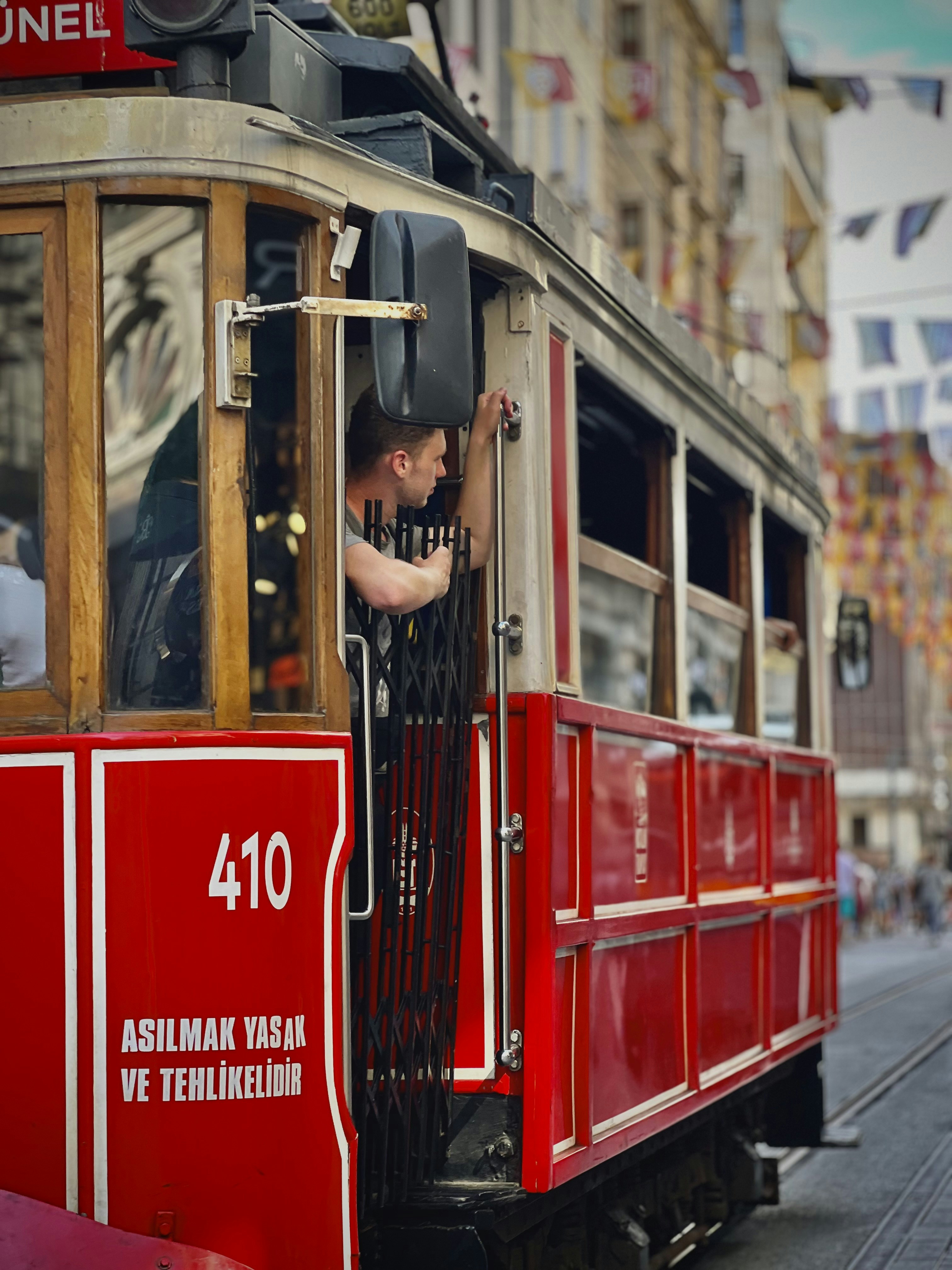A red trolley car traveling down a street next to tall buildings