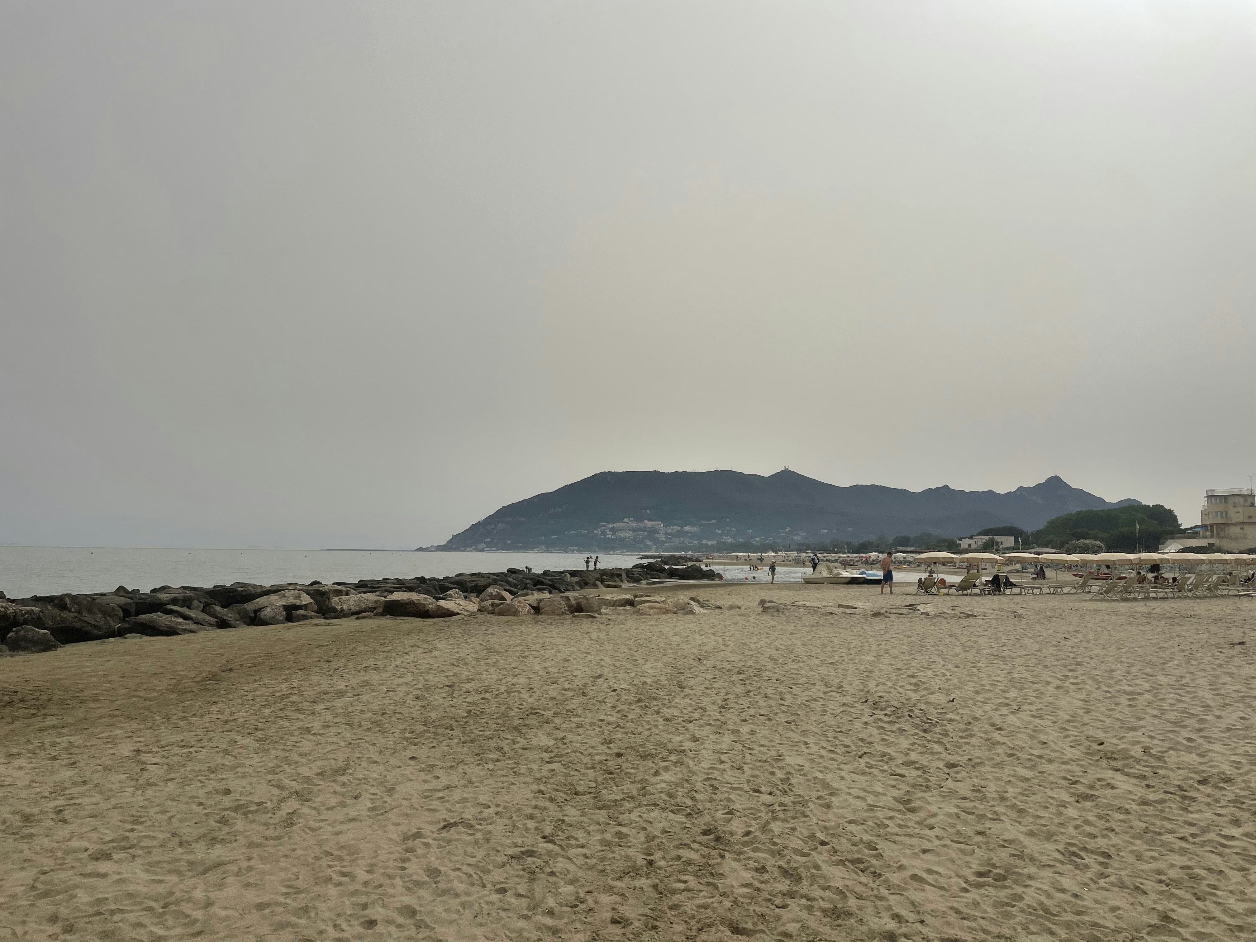 A sandy beach with a lighthouse on a hill in the distance