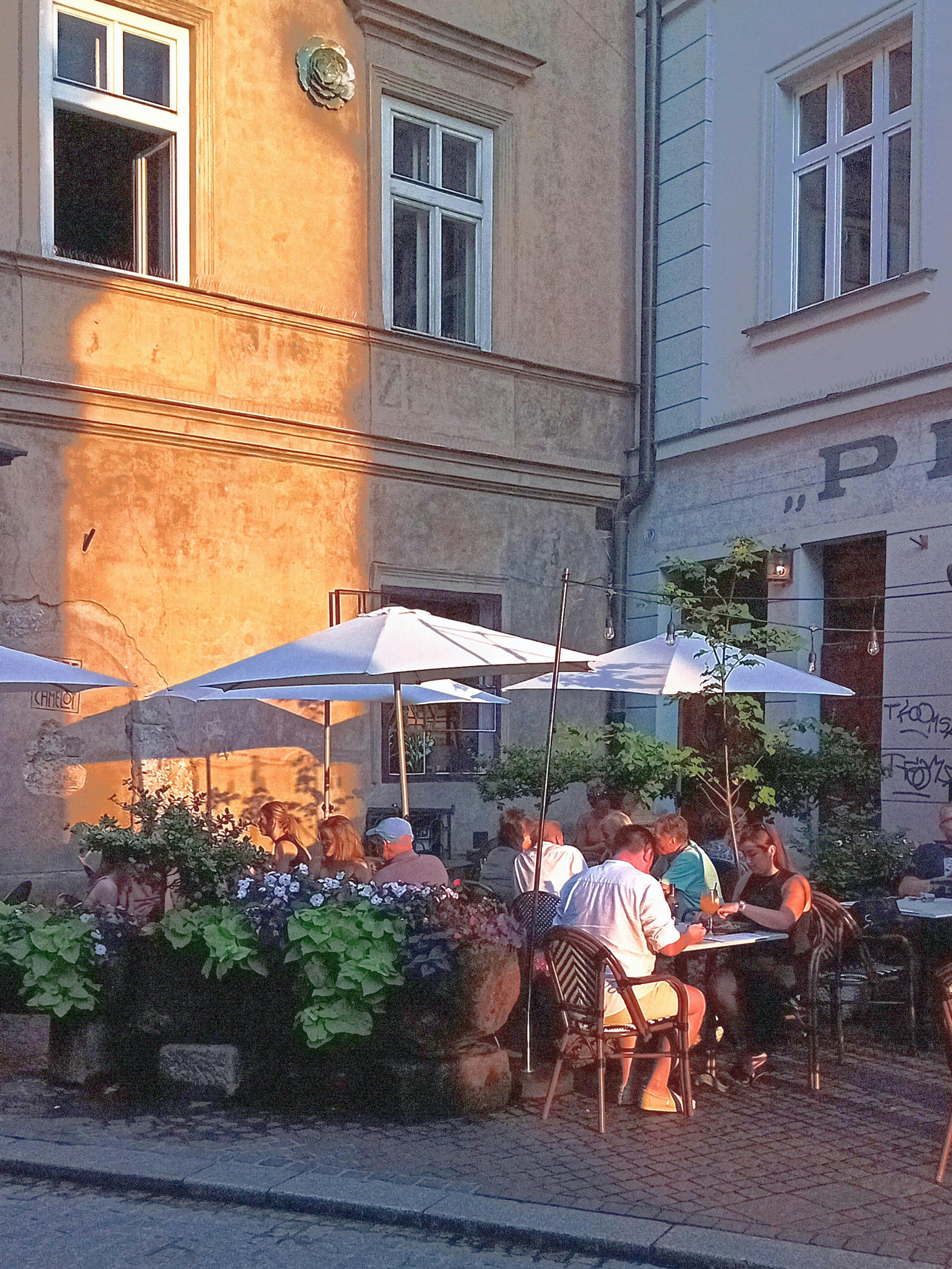 A group of people sitting at a table under umbrellas