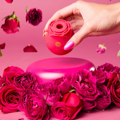 A woman's hand reaching for a pink vase with roses on it