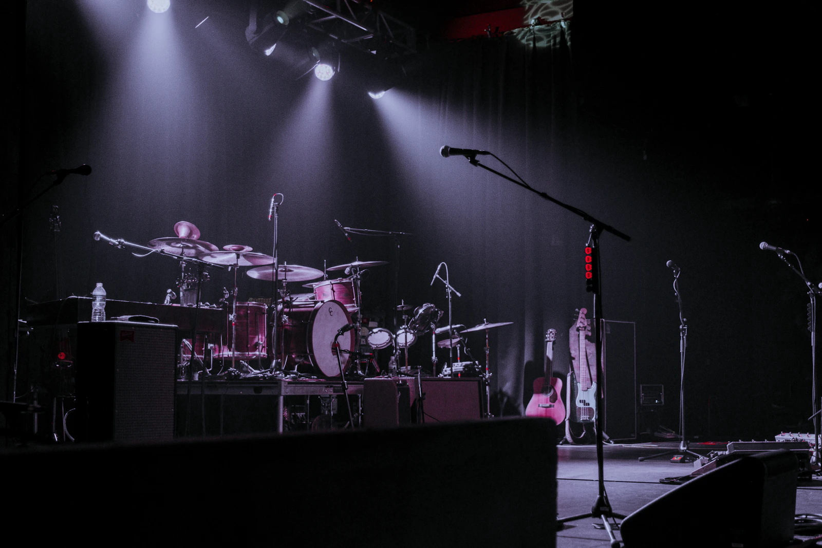 Concert stage with drums, guitars, microphones, and equipment prepared for soundcheck