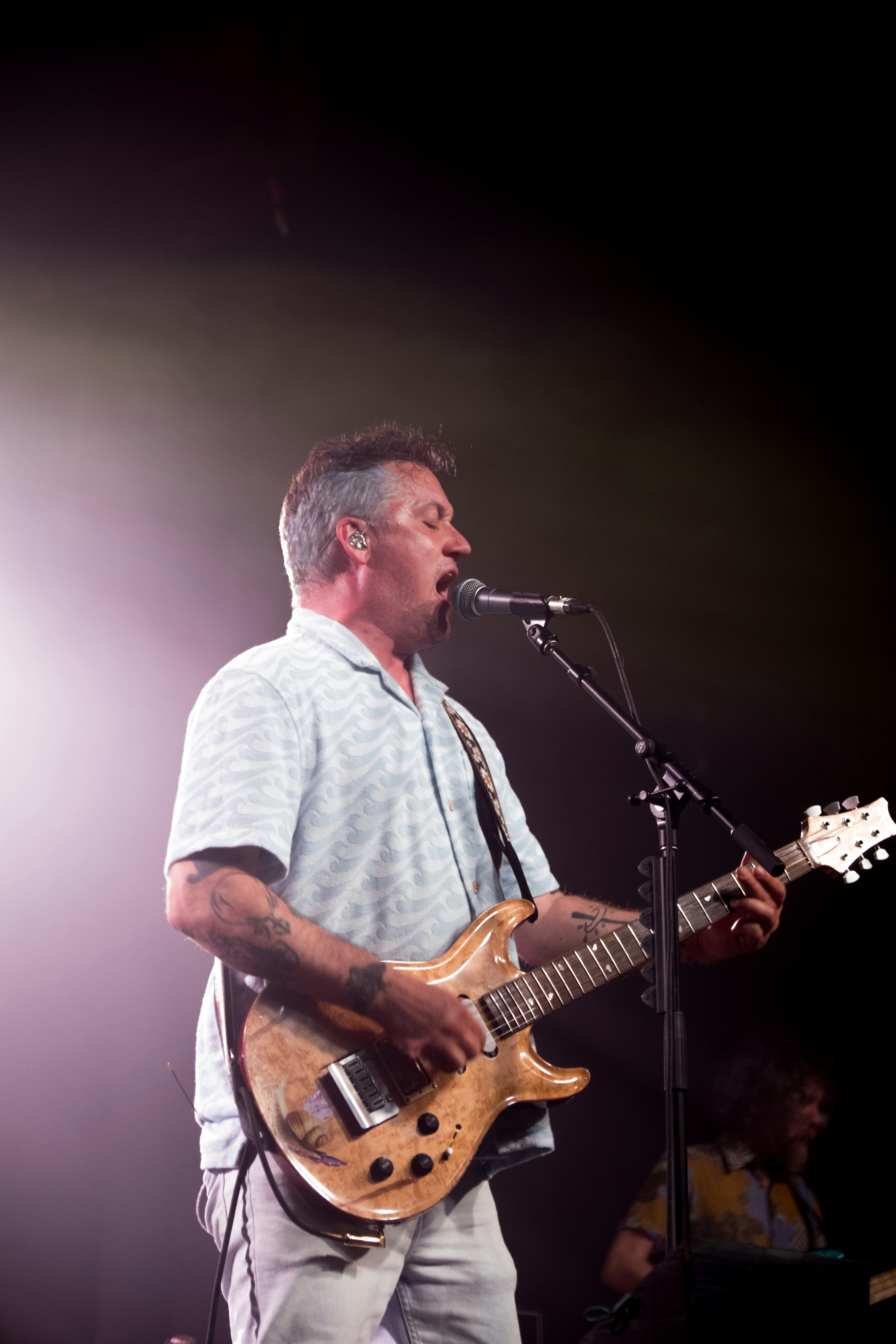 A man standing in front of a microphone while playing a guitar