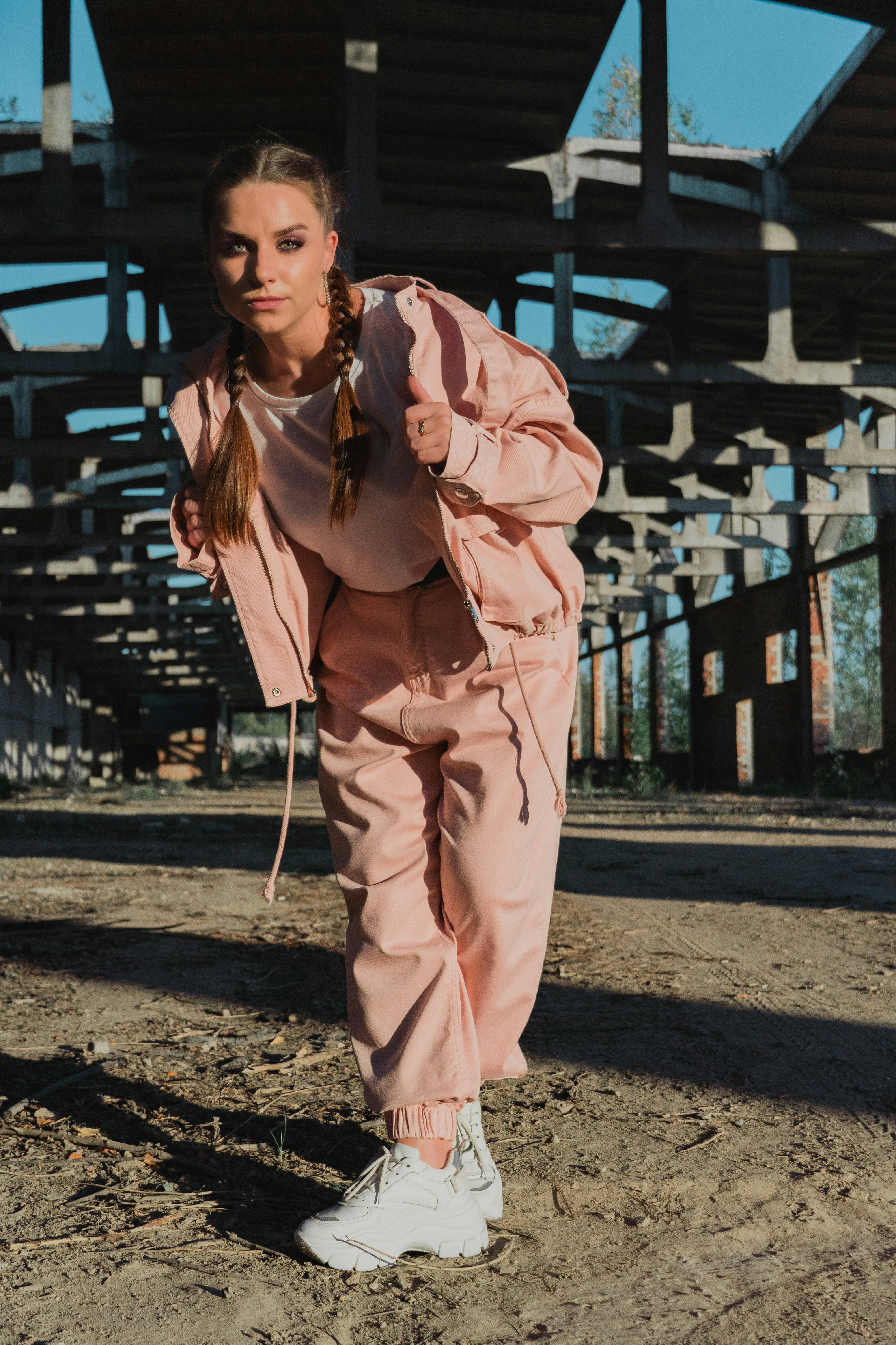 A woman in a pink outfit is standing in the dirt