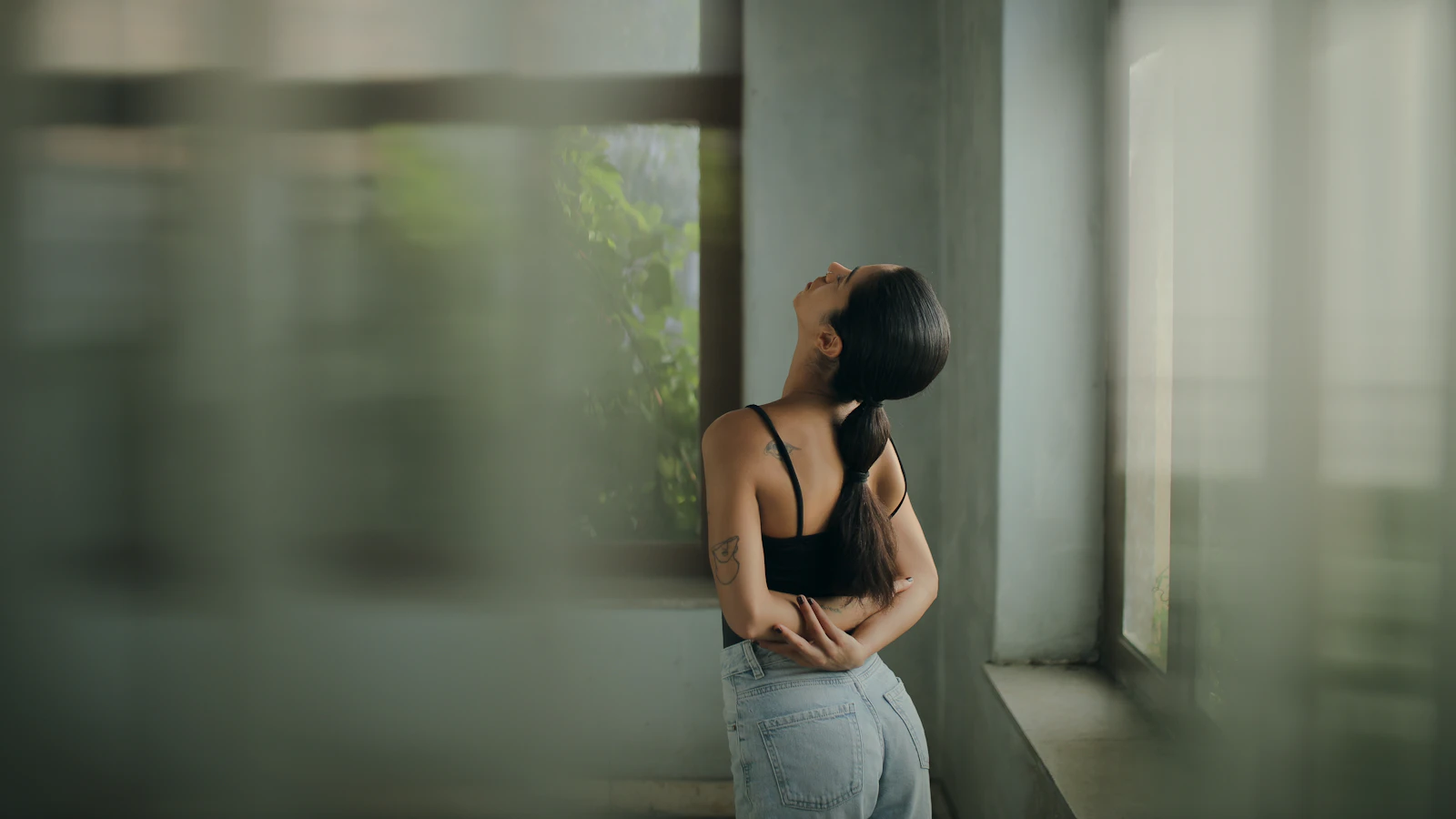 A woman leaning against a wall with her head in her hands, representing the body bracing for pain before anything has happened
