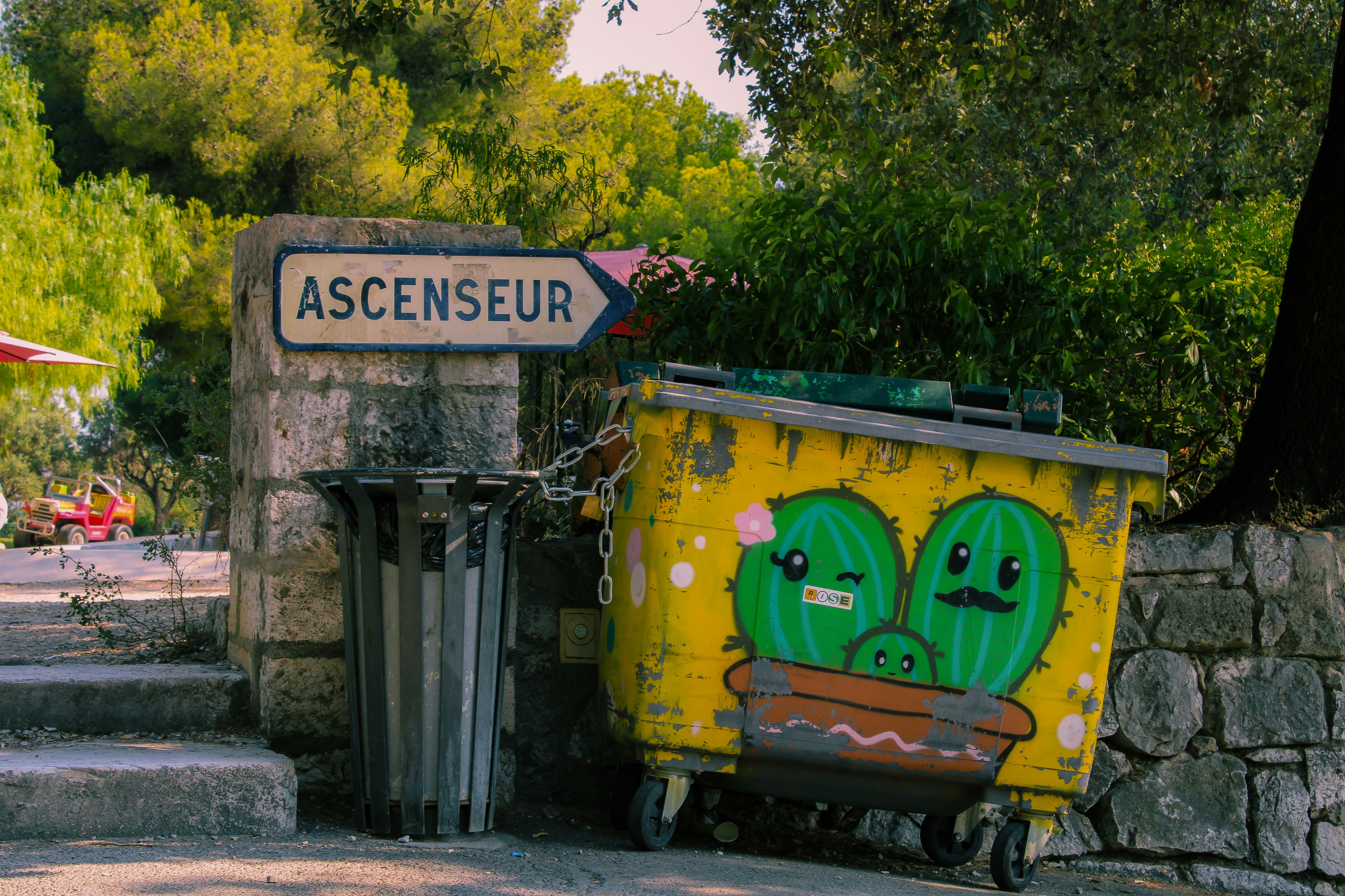 A yellow trash can sitting on the side of a road