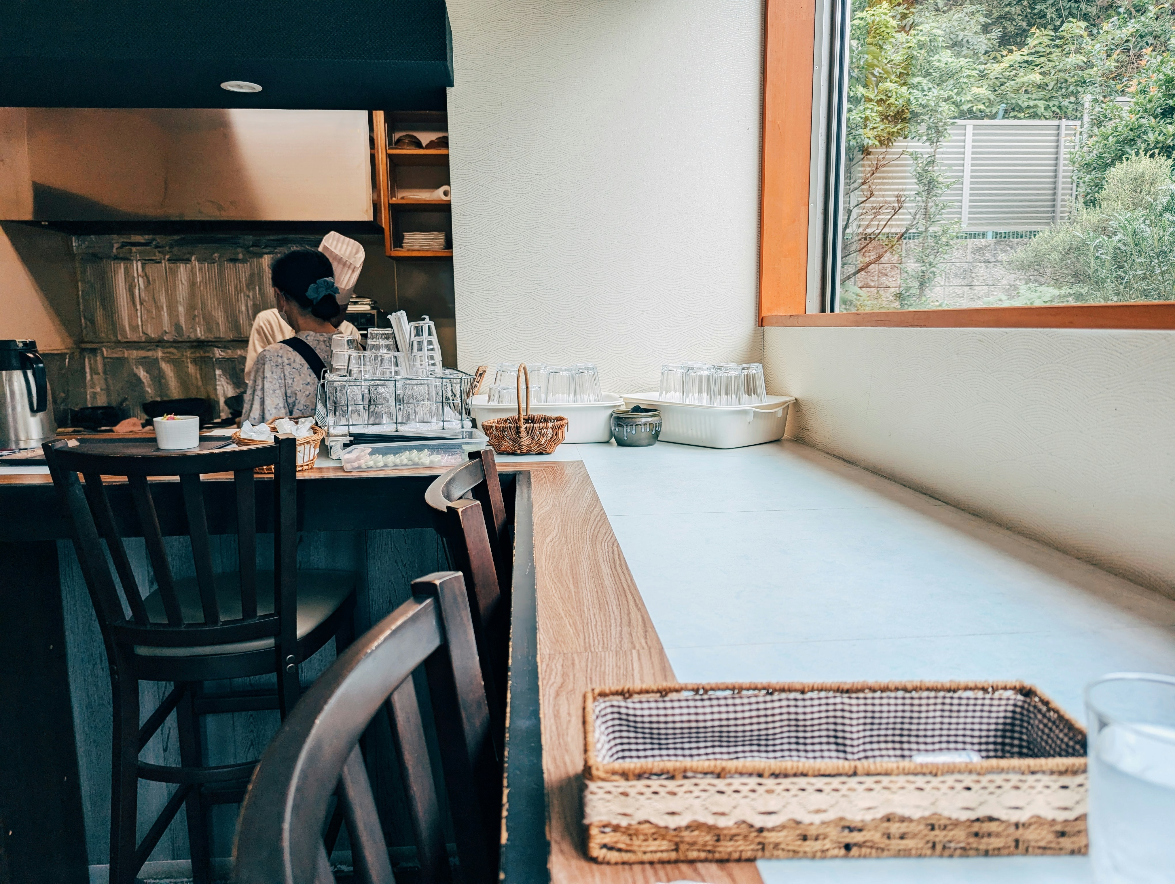A woman standing at a counter in a restaurant, 