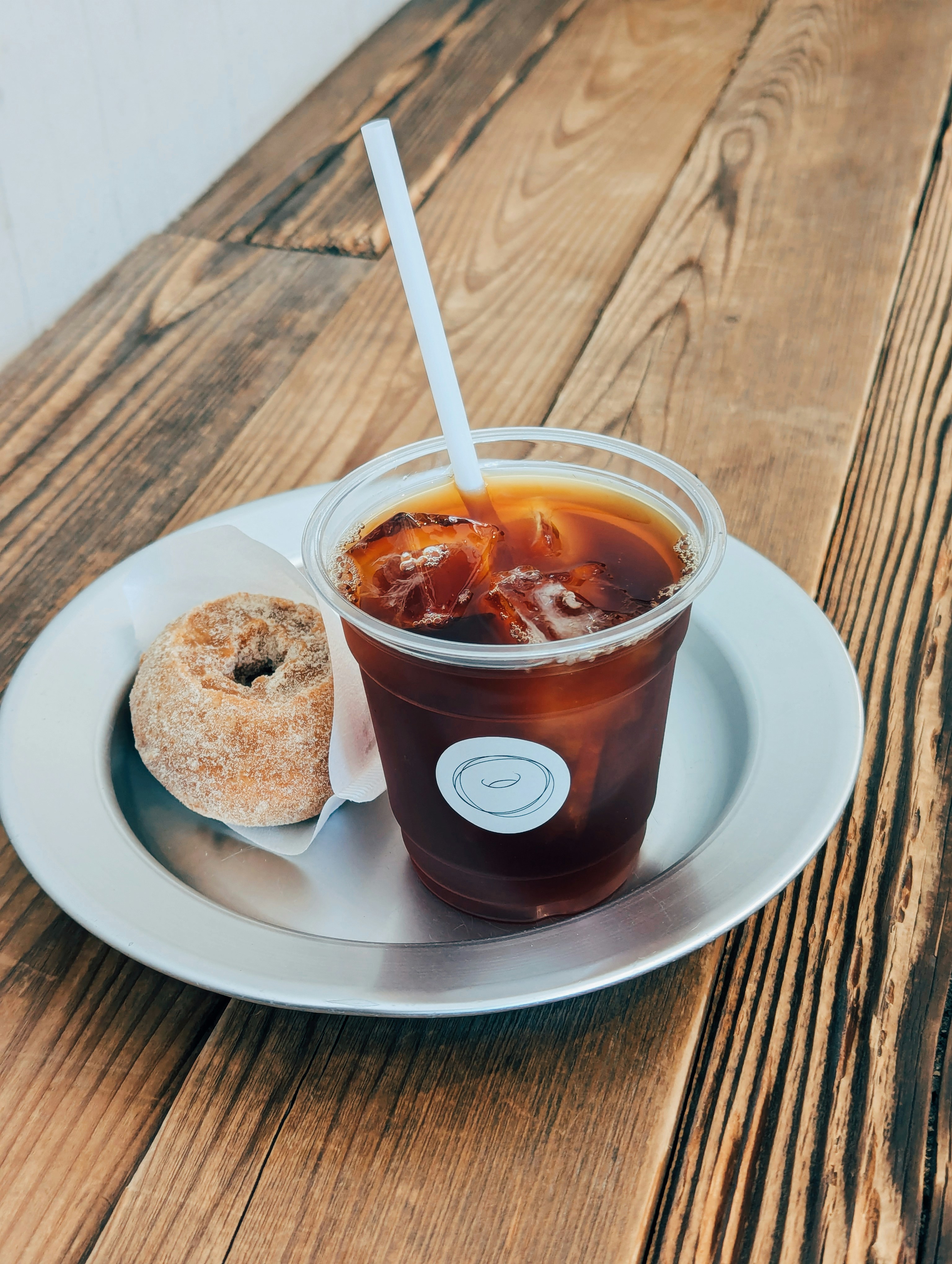 A cup of iced tea and a donut on a plate