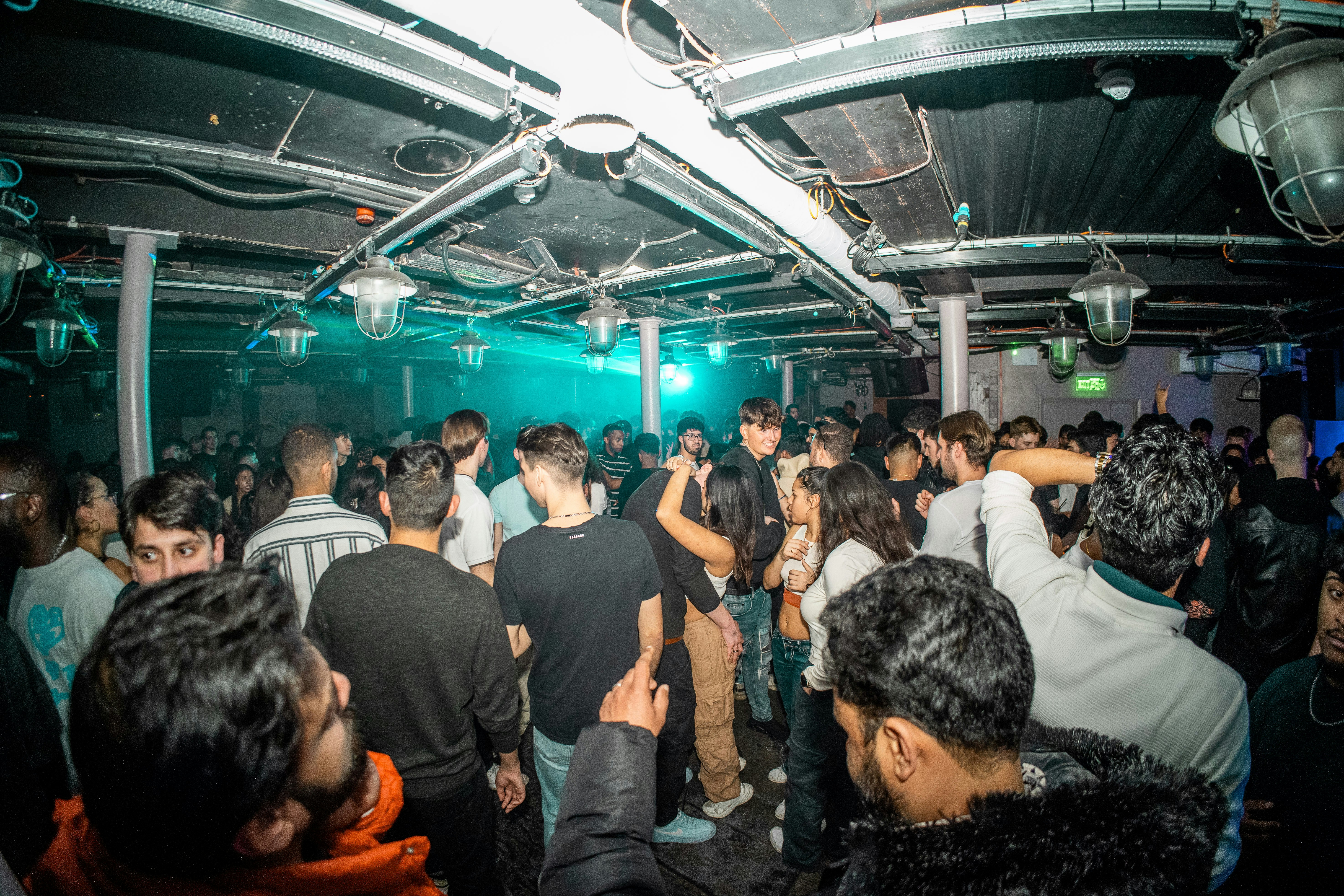 En gruppe mennesker danser sammen inde på en overfyldt klub.
