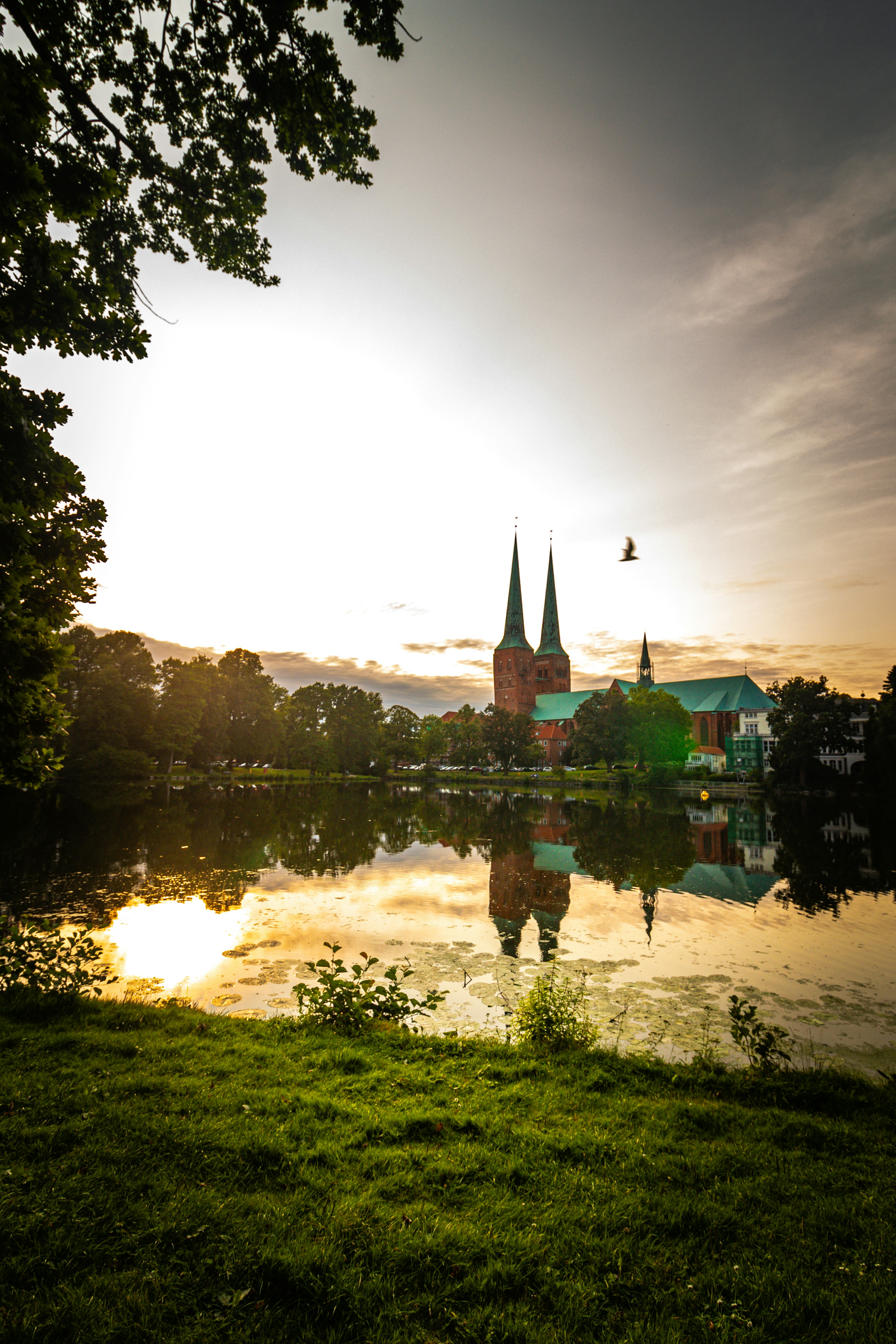 The sun is setting over a lake with a castle in the background