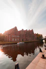 A boat is on the water in front of a large brick building